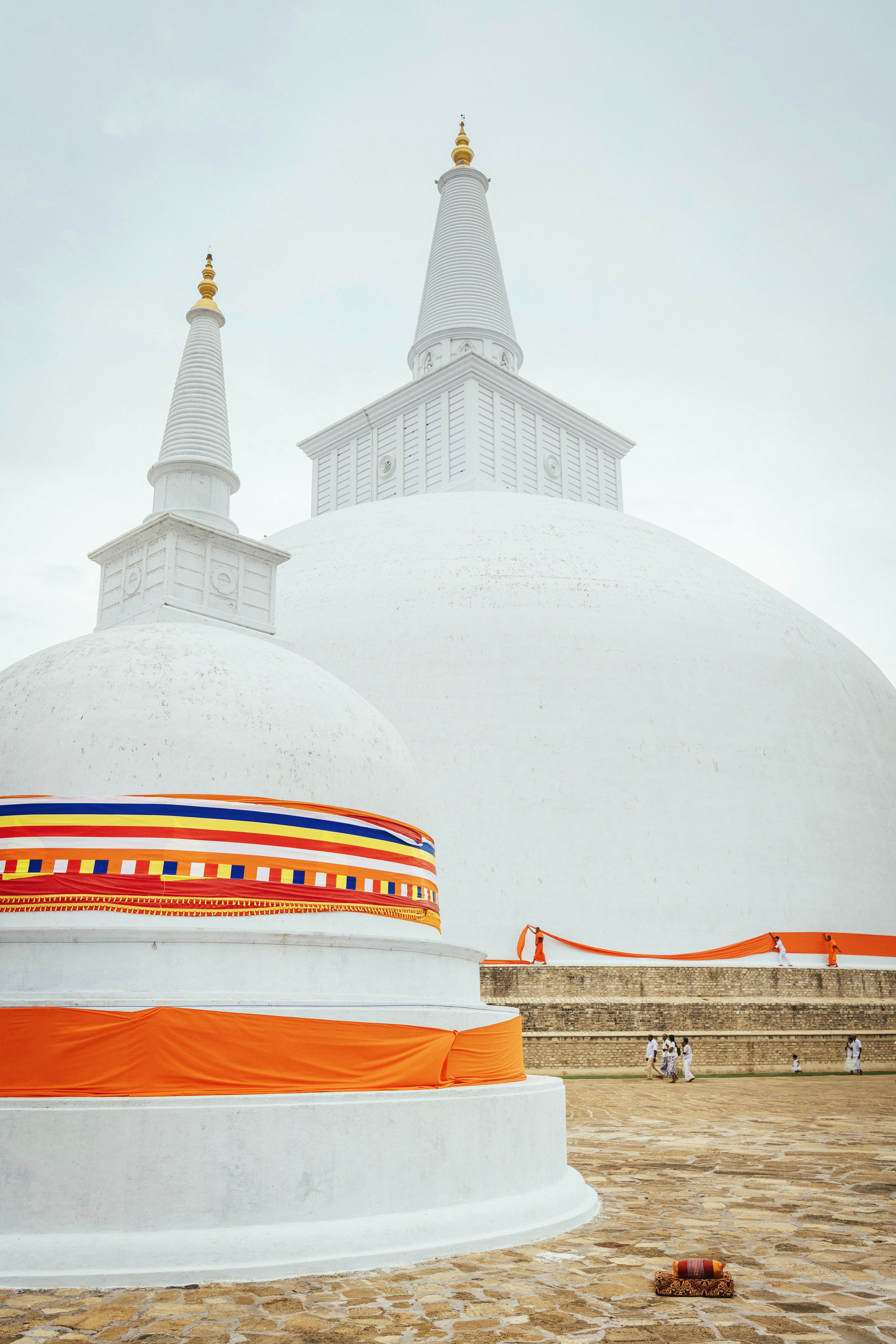 White domed structures with pointed spires are wrapped in orange-patterned material in Sri Lanka.