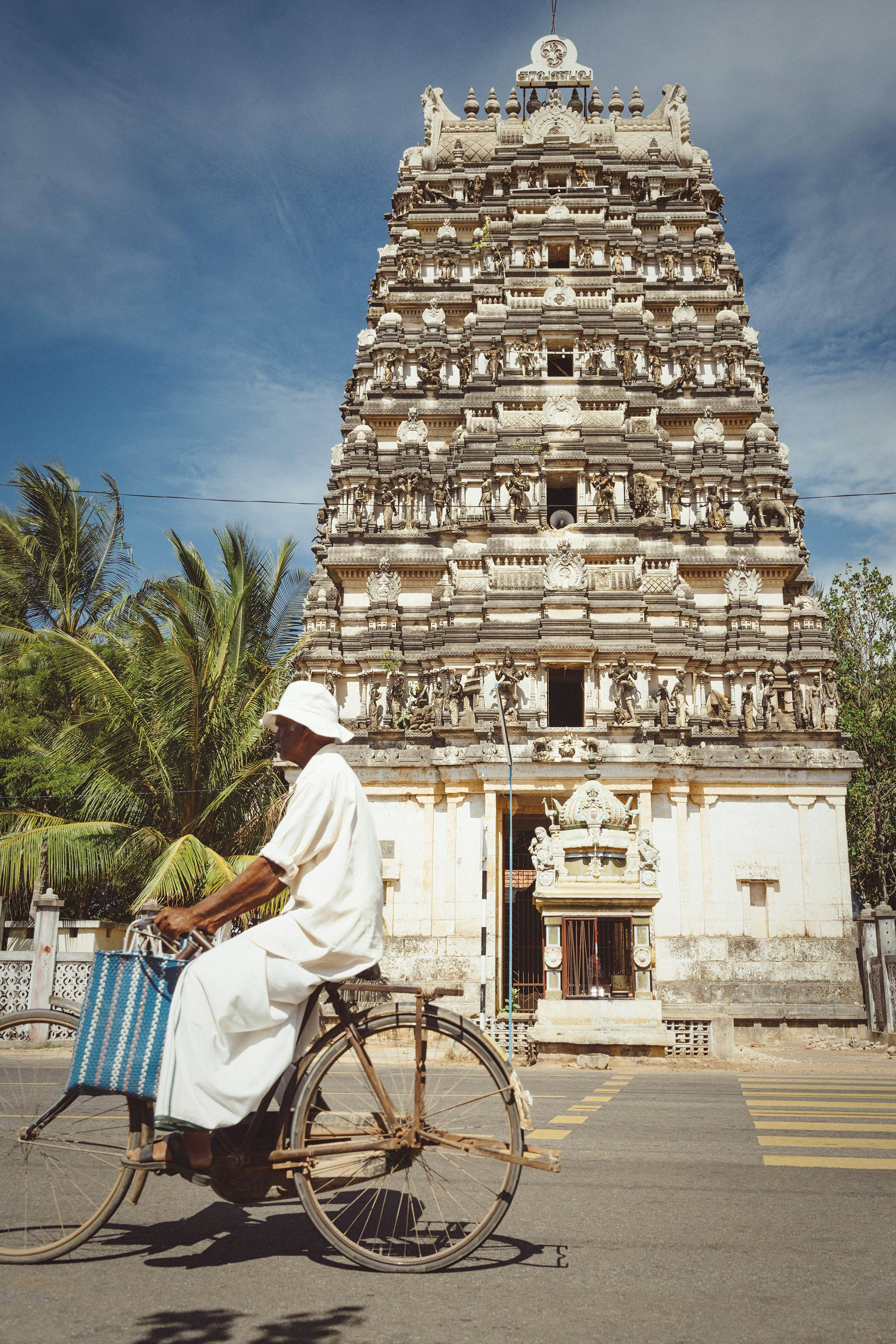 A man on a bicycle passes a statue-laden temple in Sri Lanka.