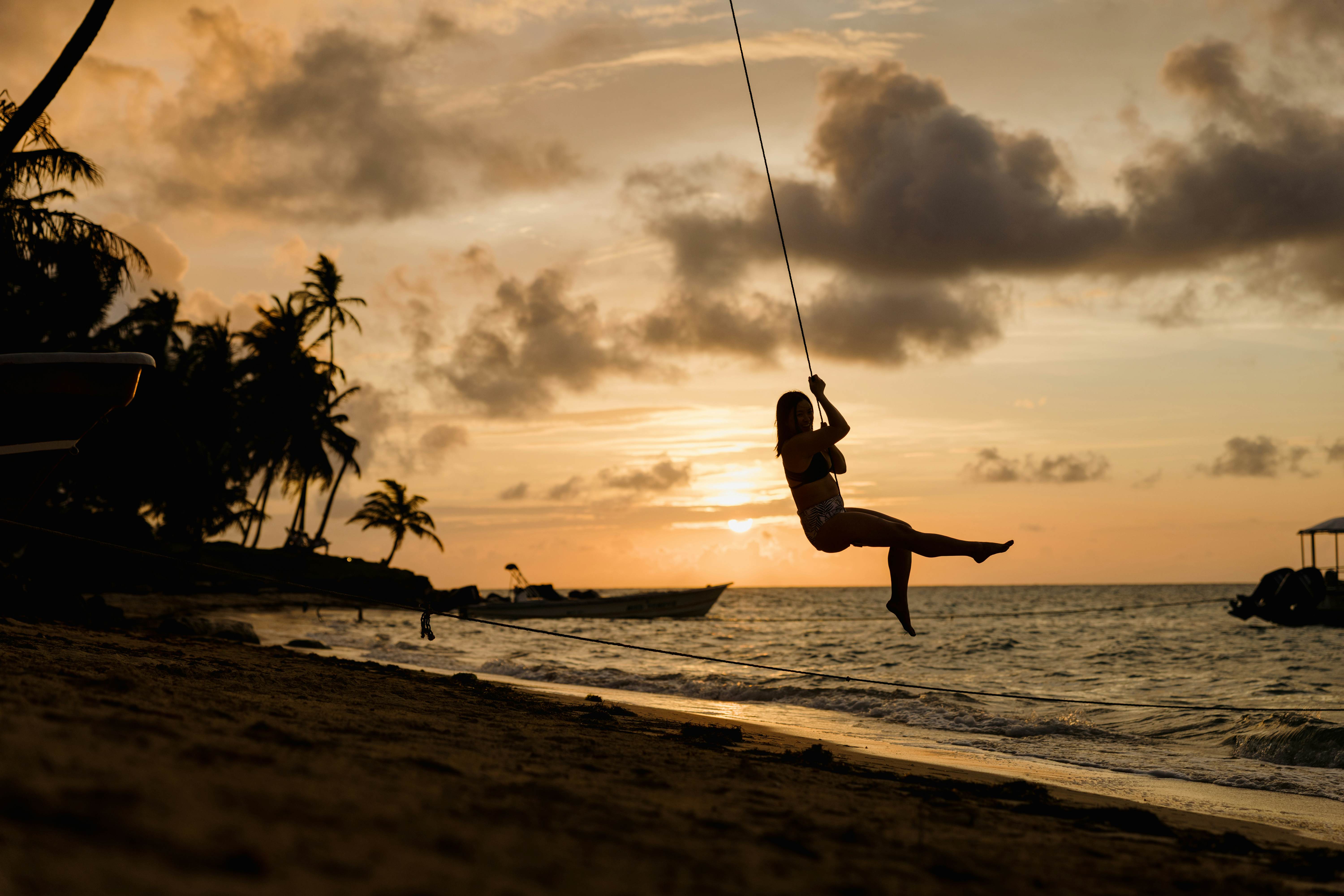 Woman on a swing tied to a palm tree at sunset. Little Corn Island, Nicaragua. May 2025.