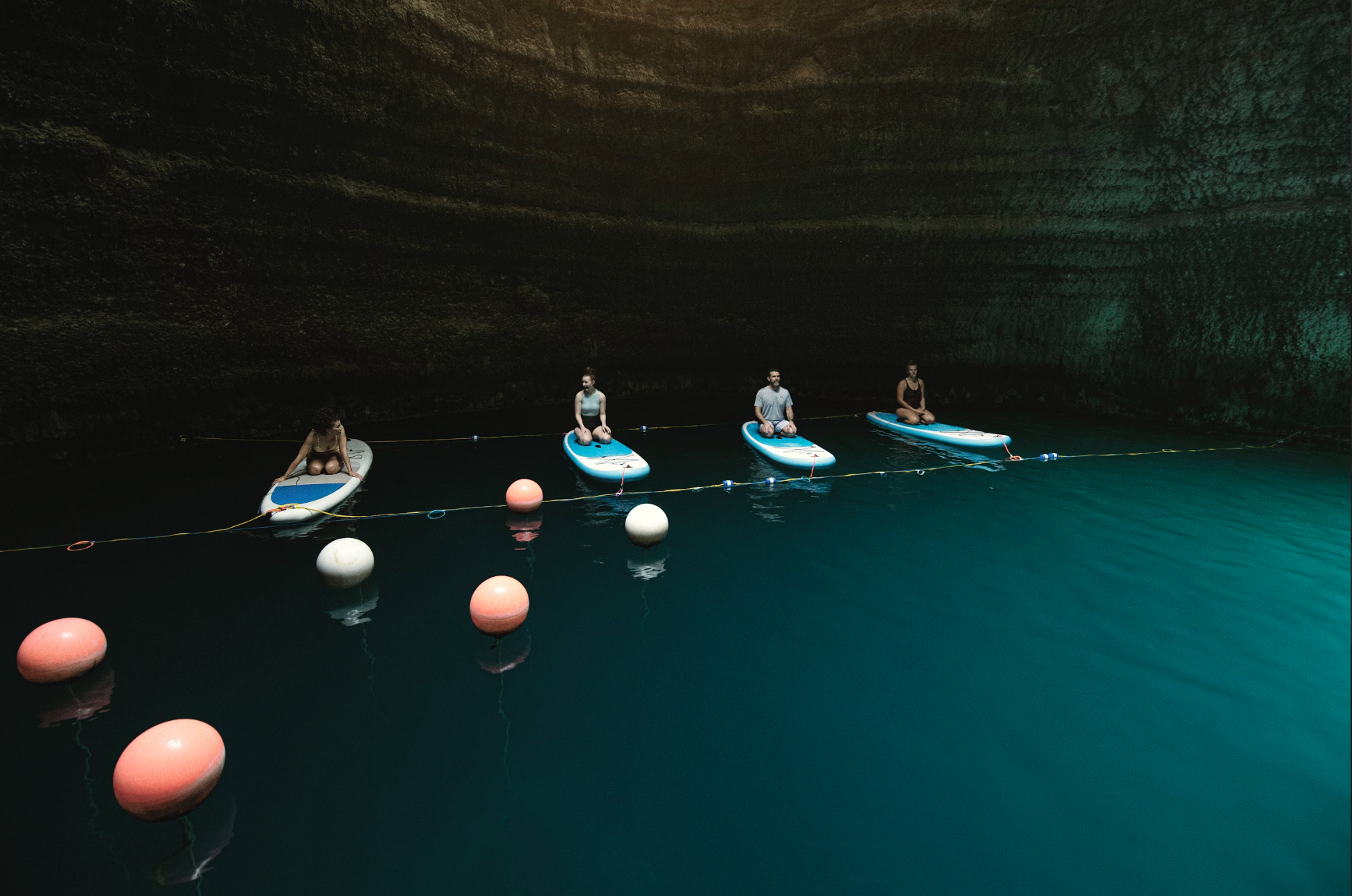 Four people sitting on paddleboards.  