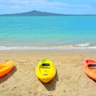 Auckland  New Zealand - November 21 2020: View of three colourful kayaks at Mission Bay with Rangitoto Island in background  License Type: media  Download Time: 2022-04-28T10:23:46.000Z  User: aniabartoszek  Is Editorial: Yes  purchase_order: