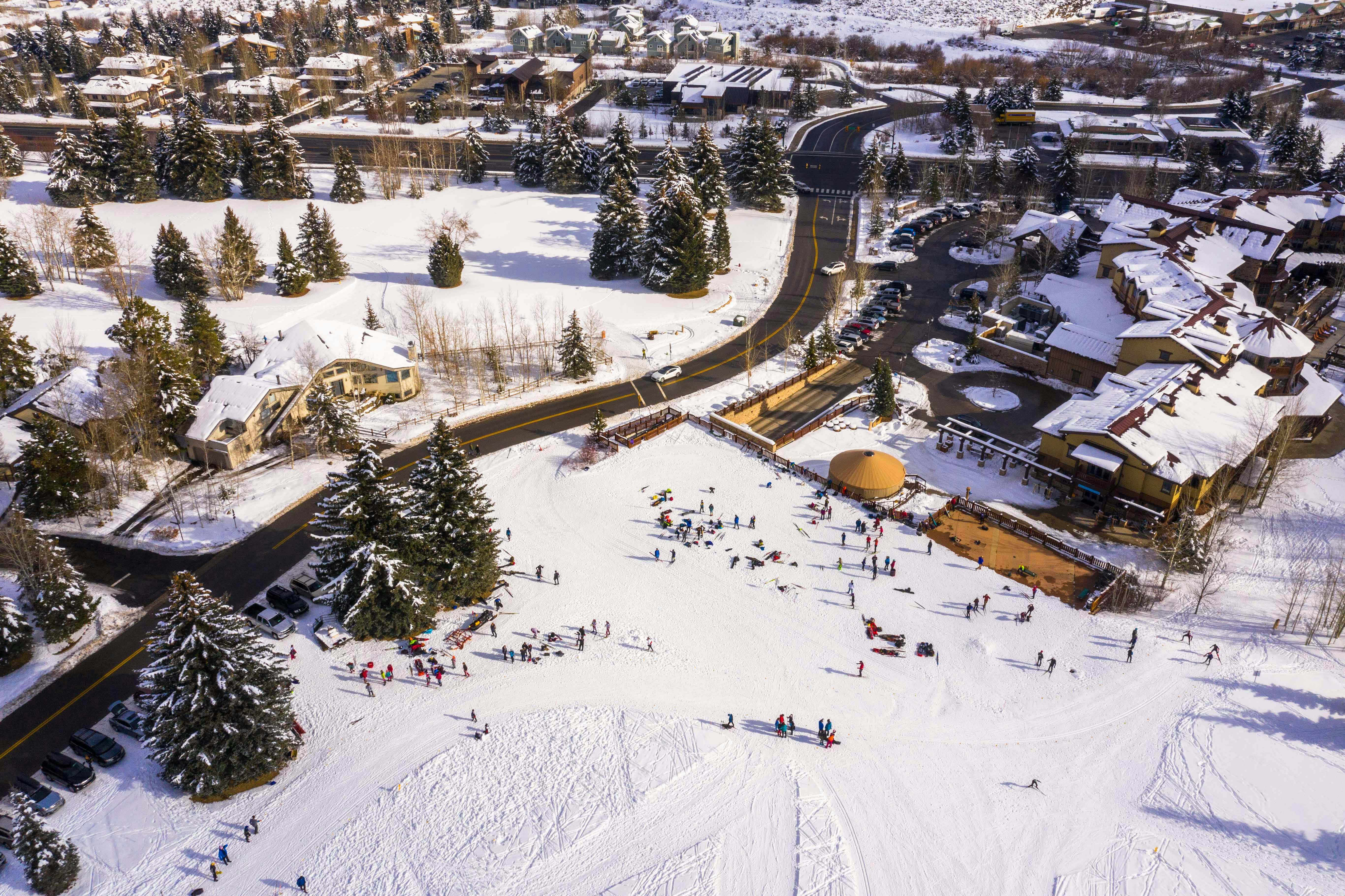 Aerial shot of Nordic ski center with sa curved driving road dividing two snowy areas on a sunny day.
