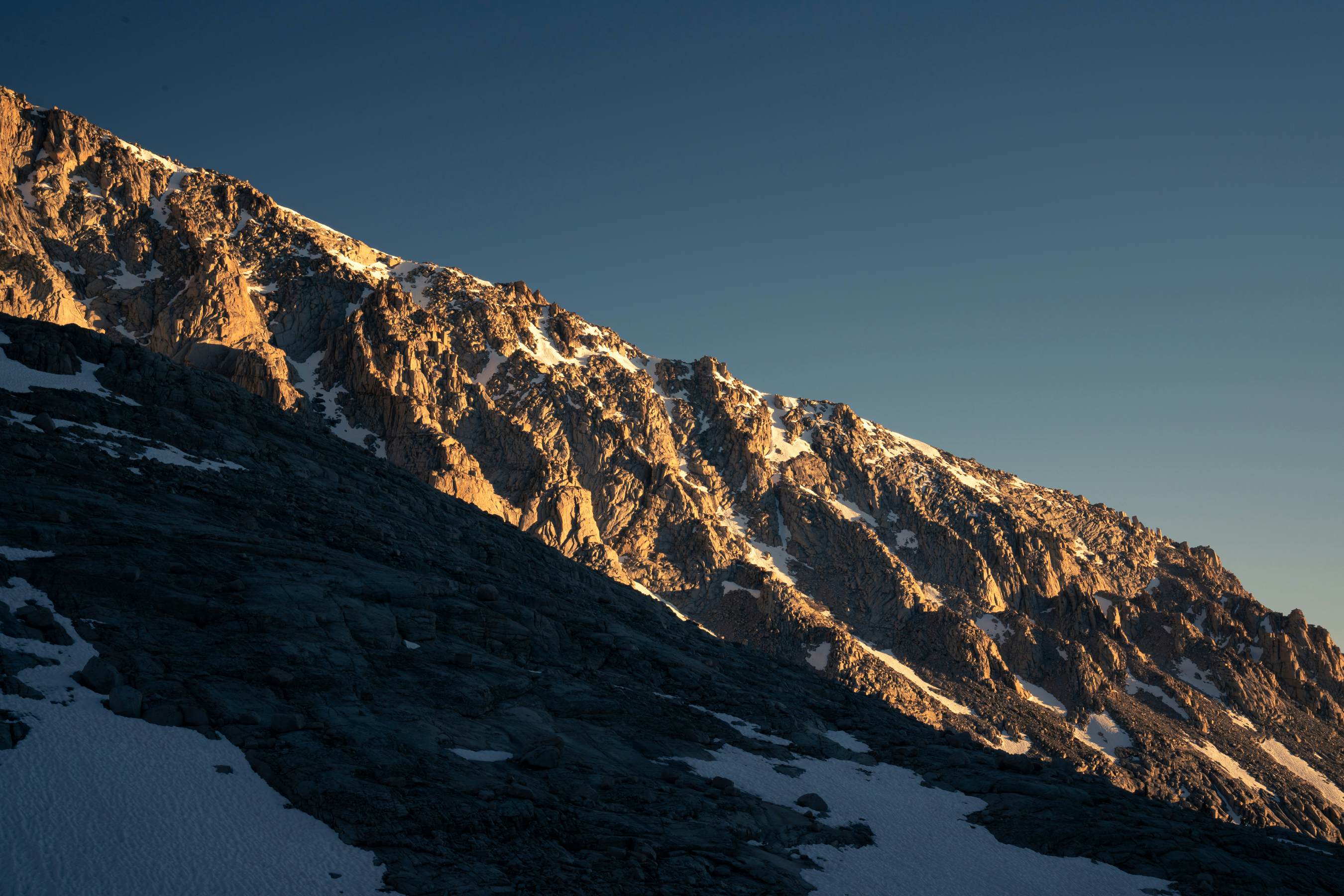 Ripples of rock in a cliff face glow in the setting sun.