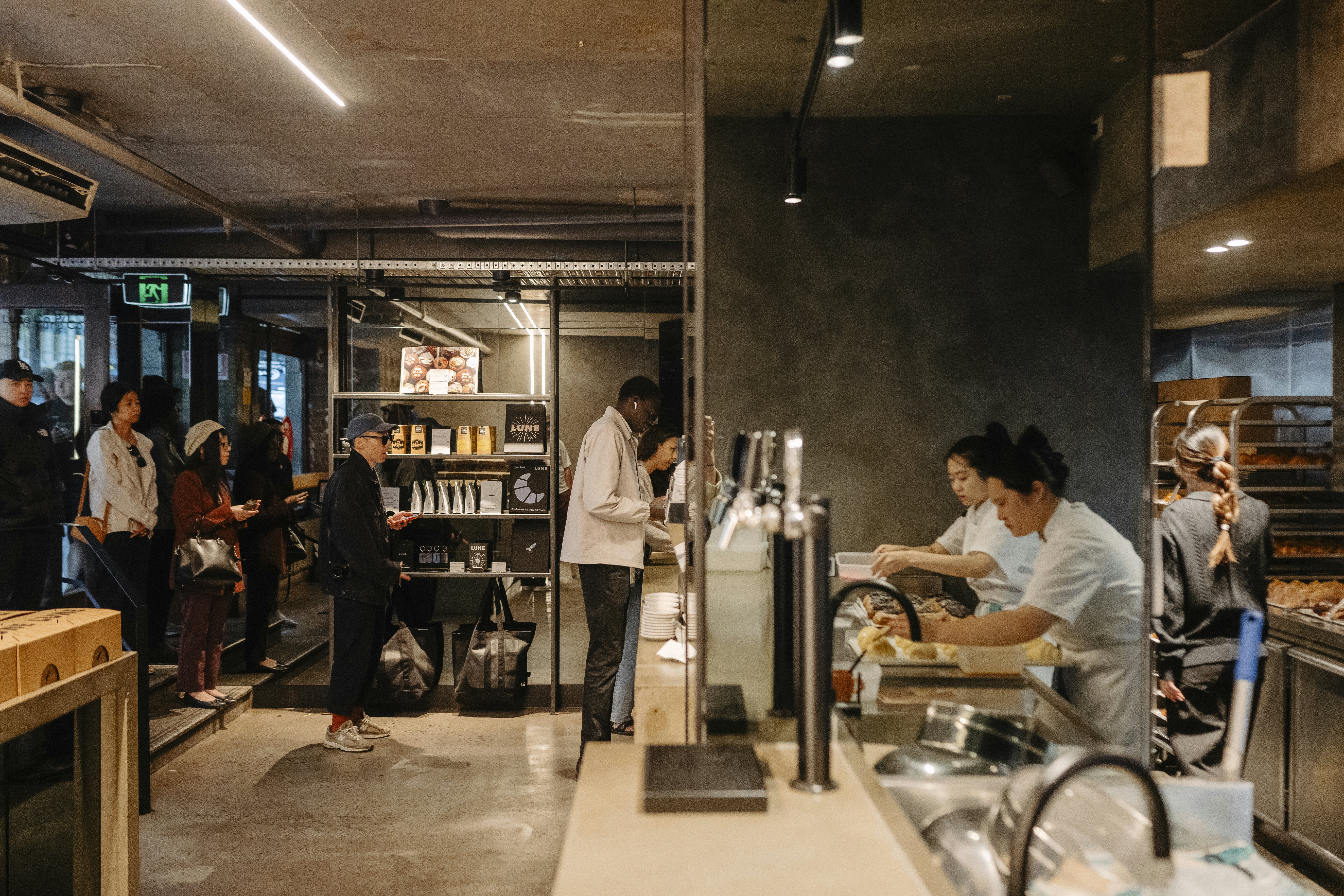 Customers in a bakery while pastry chefs make pastries