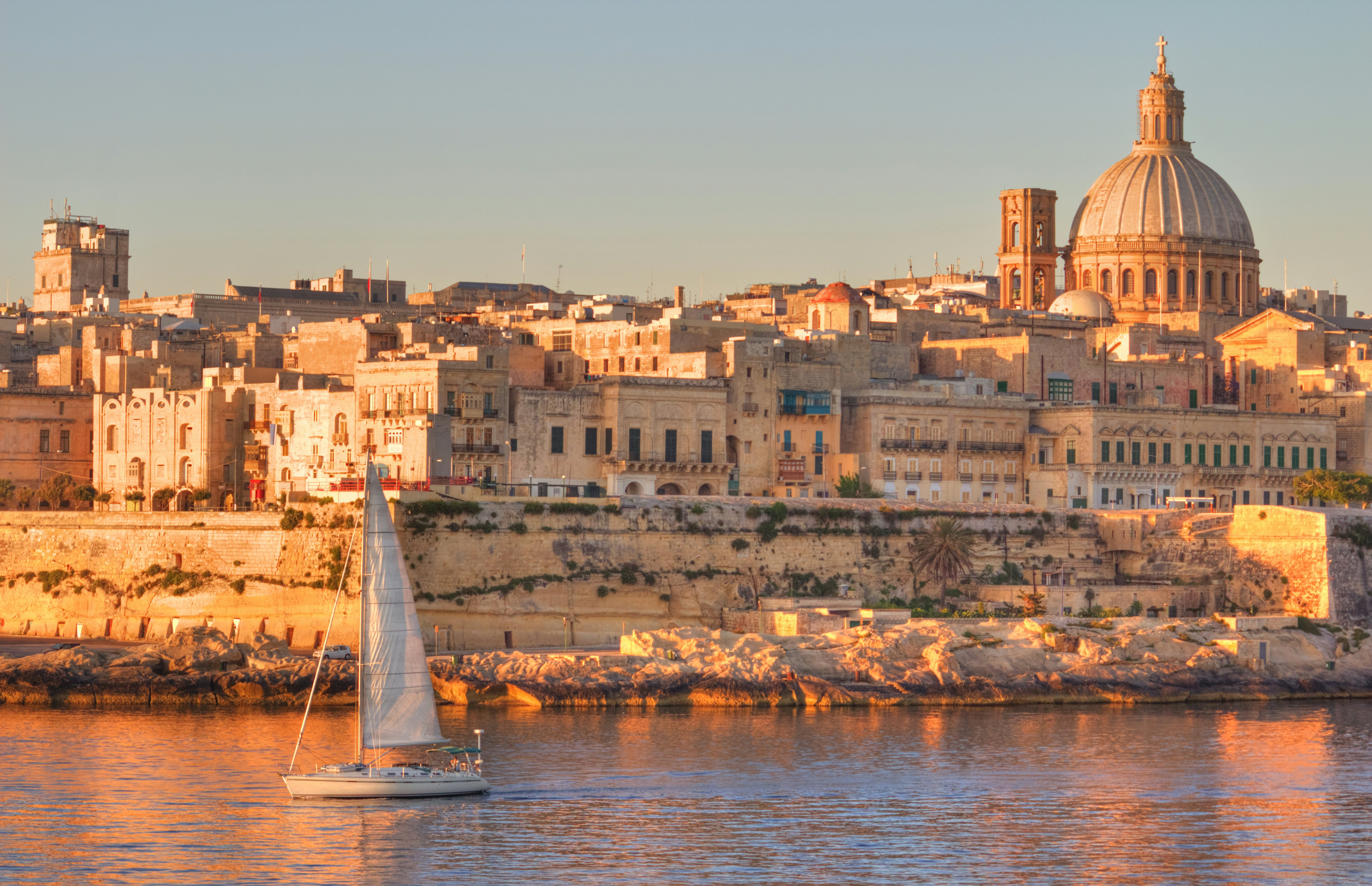 A limestone city shines in the morning light by the water.