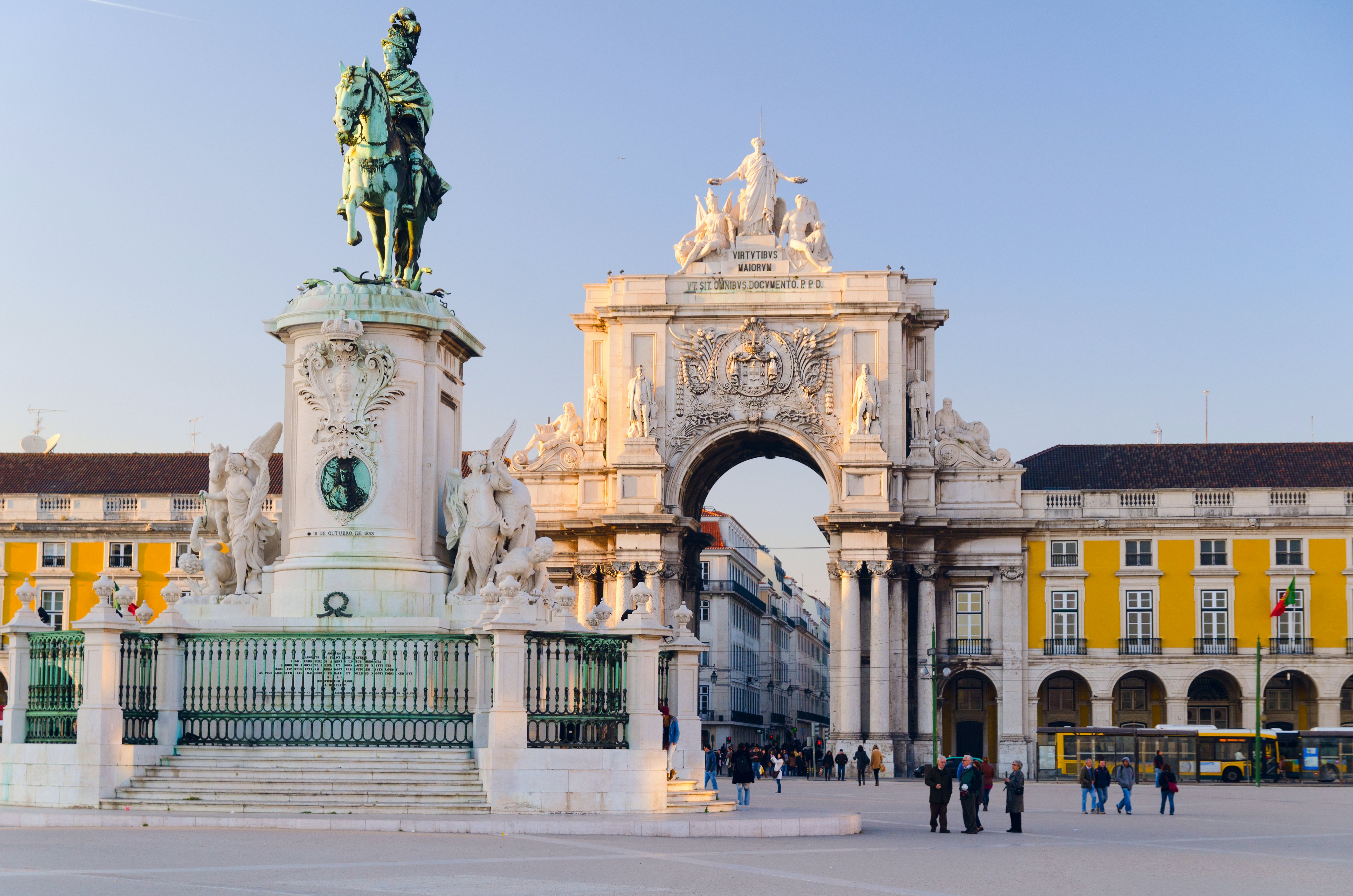 A large city square with a central statue of a man on horseback, backed by a large ornate archway. People walk by dressed in warm winter clothes.