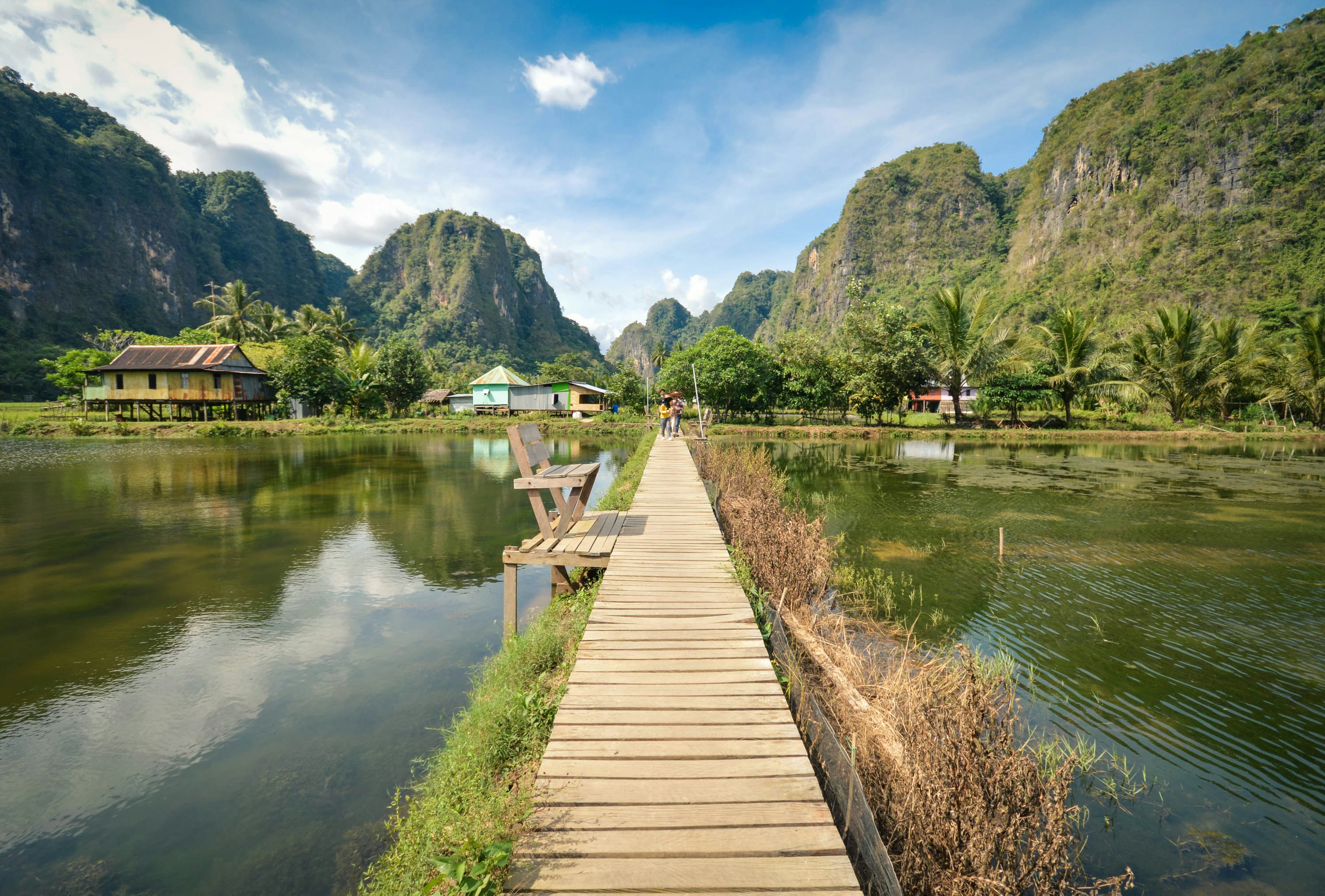 A boardwalk leads to village houses and karst outcrops at Rammang Rammang near Makassar, Sulawesi, Indonesia.