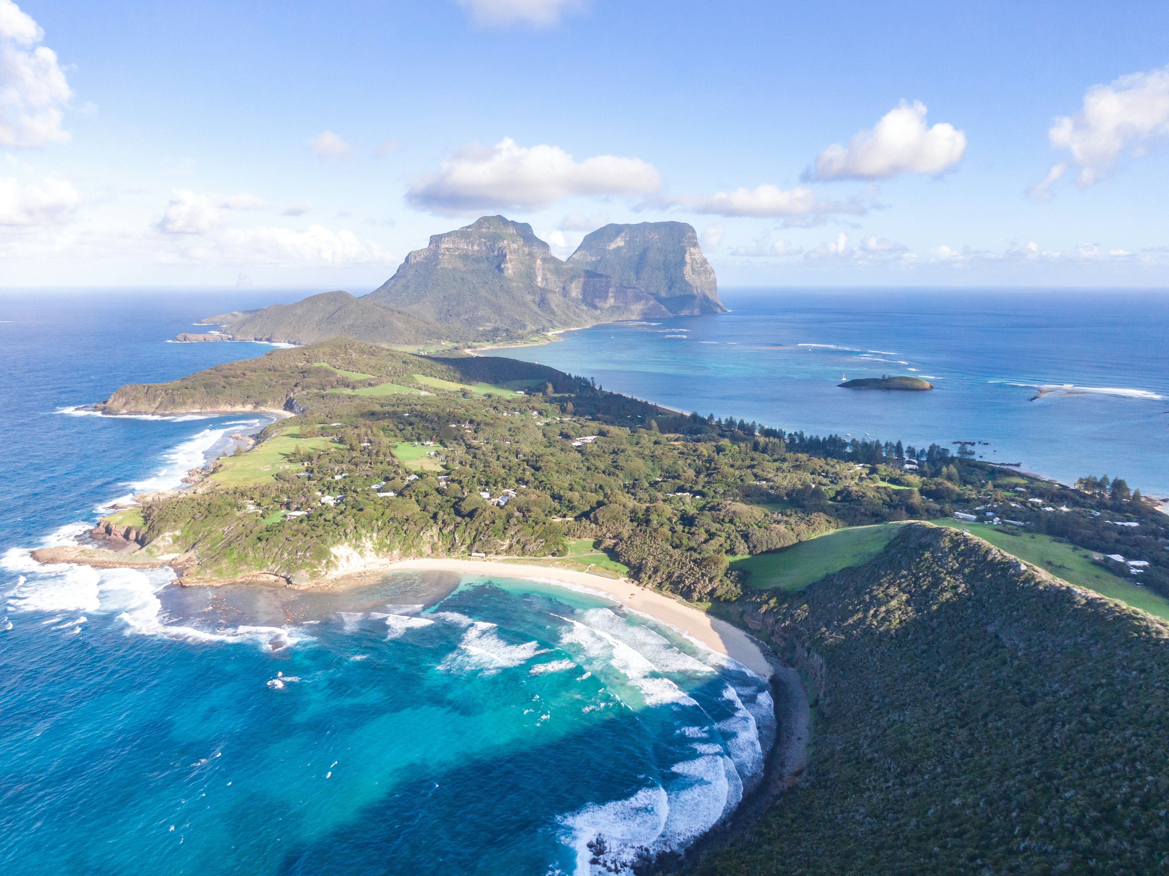 A drone view of an island with water lapping green shores