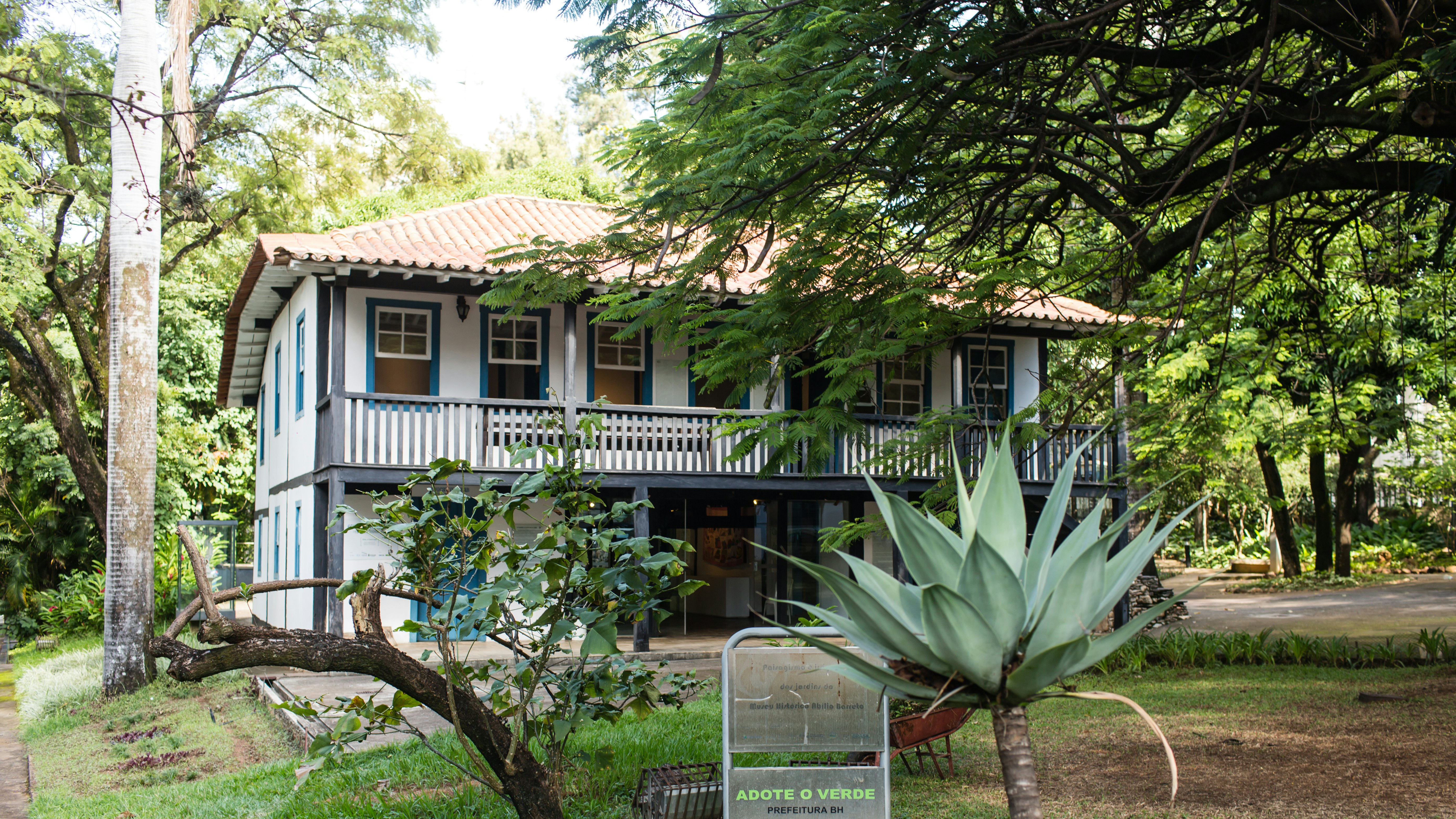 A two-floor, light-colored building with dark trim. A large tree partially obscures the second floor.
