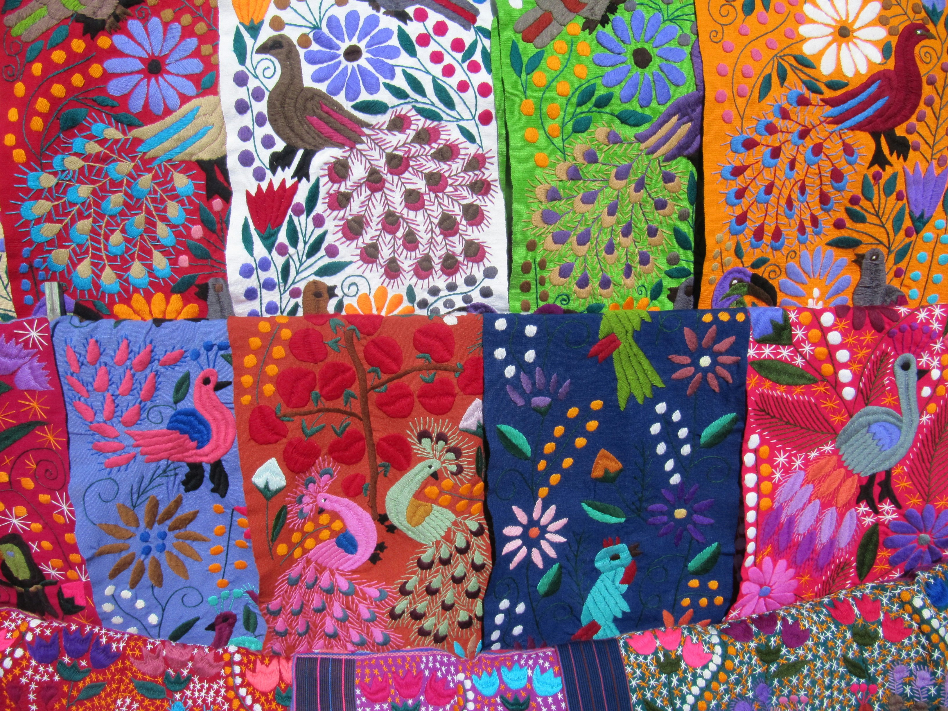 Colorful woven cloth in pinks, purples, greens, and blue, with images of peacocks and flowers.
