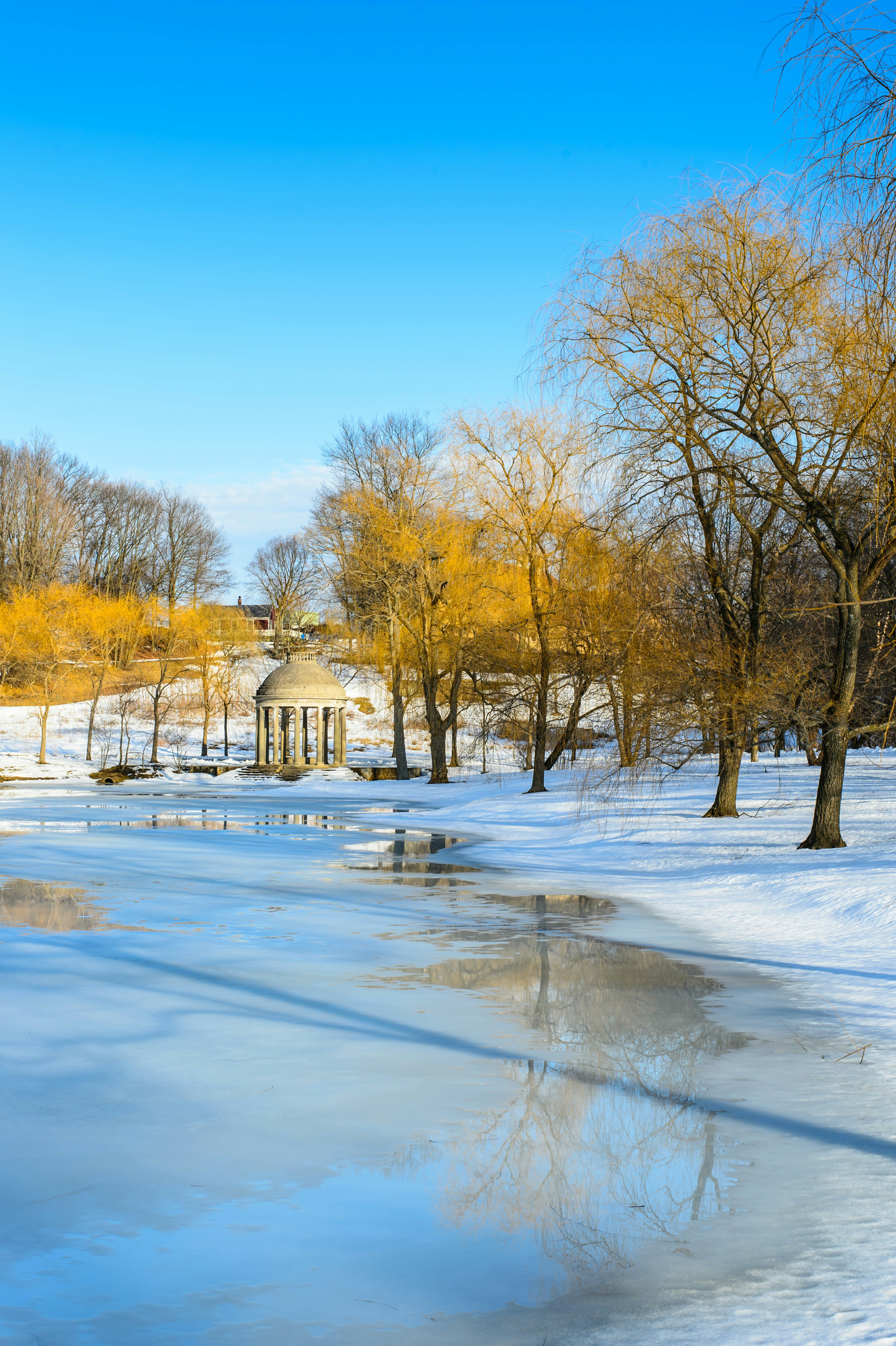 A stone gazebo in a snow-covered park