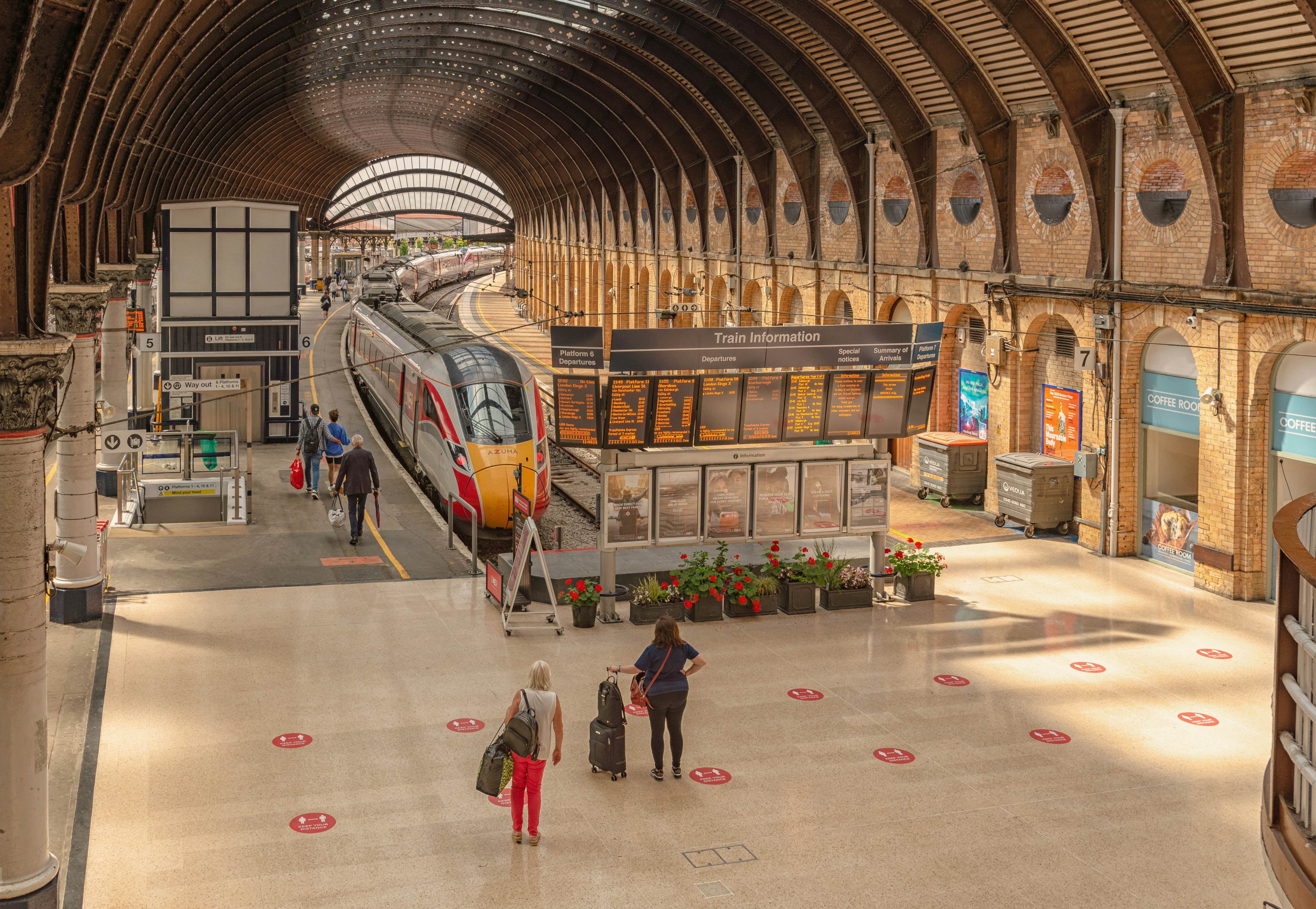 York, UK. July 28, 2021.  A station concourse with a station electronic notice board and a train waiting to depart.   Passengers are on the platform and an elaborate 19th Century canopy is overhead., License Type: media, Download Time: 2025-09-18T17:36:28.000Z, User: rhylton_redventures, Editorial: true, purchase_order: 65050 - Digital Destinations and Articles, job: Lonely Planet, client: England train stations article , other: Rhianydd Hylton