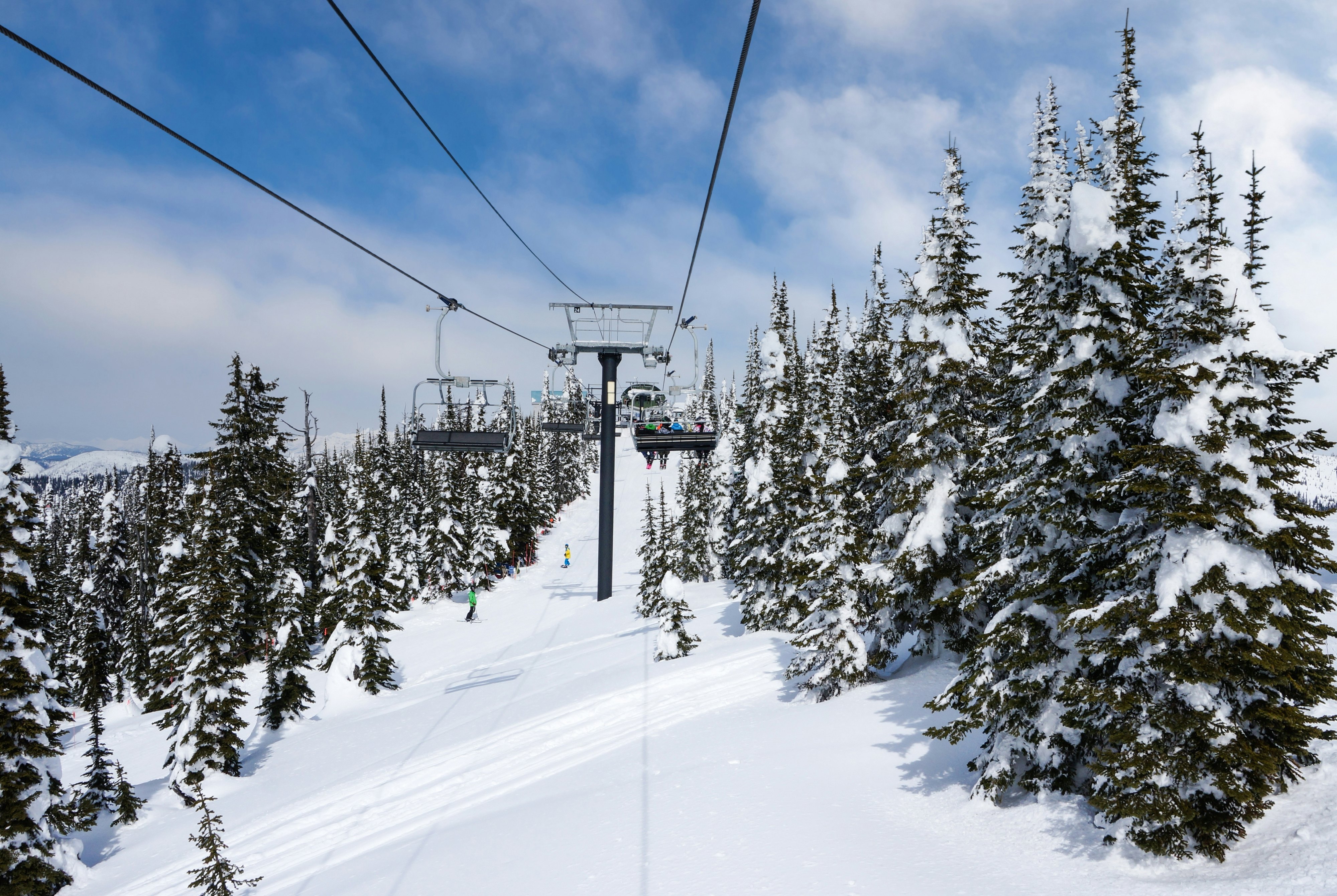 A ski chairlift goes up a mountain covered with snow