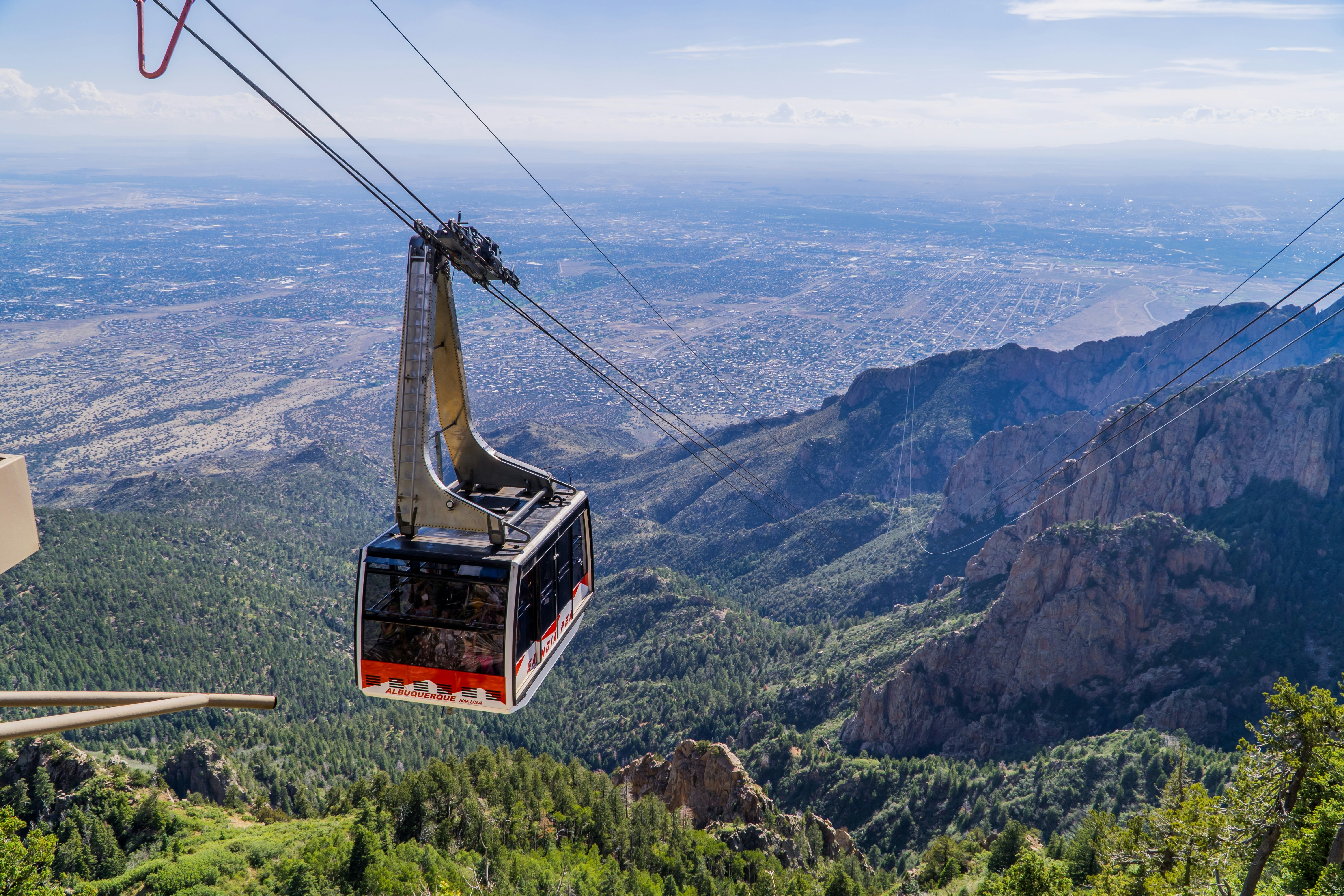 A cable car in mid-flight overlooking mountain scenery and wide, flat plains