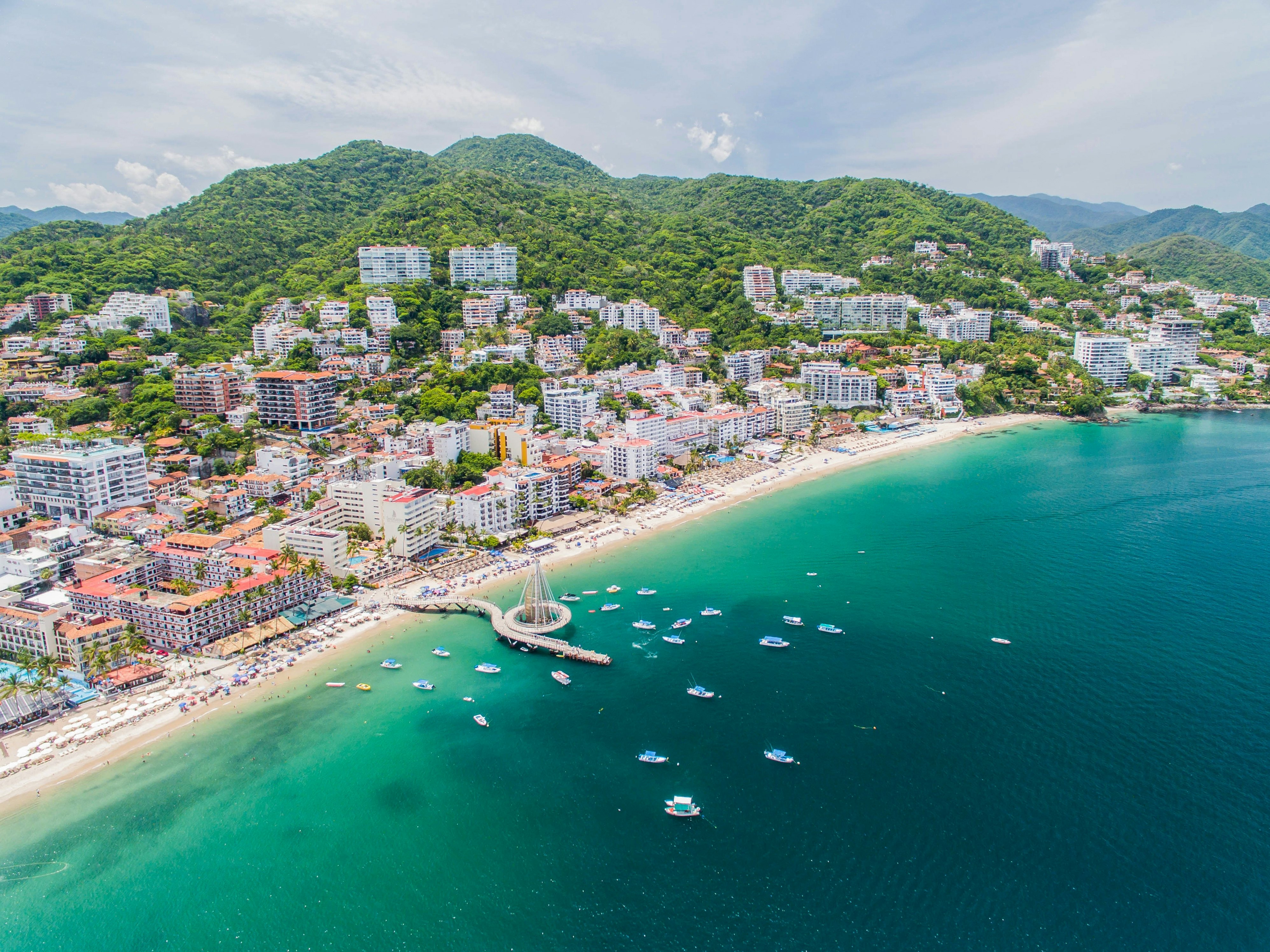 Aerial view of beachside city with boats in the water on a sunny day.