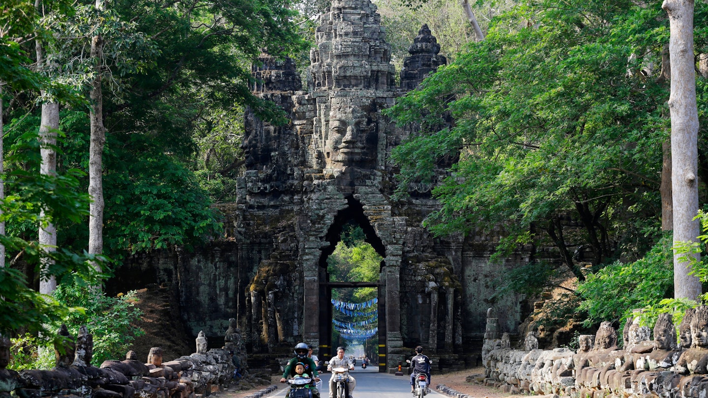 Siem Reap, Cambodia - April 2, 2023: People ride through the North Gate of Angkor Thom, part of Angkor Wat complex. The Buddhist temple is considered the largest religious monument in the world. , License Type: media, Download Time: 2025-03-06T15:36:43.000Z, User: Ppeterson948, Editorial: true, purchase_order: 56500 - T&R or Kids, job: Global Publishing WIP , client: BIT 2026, other: Pia Peterson Haggarty