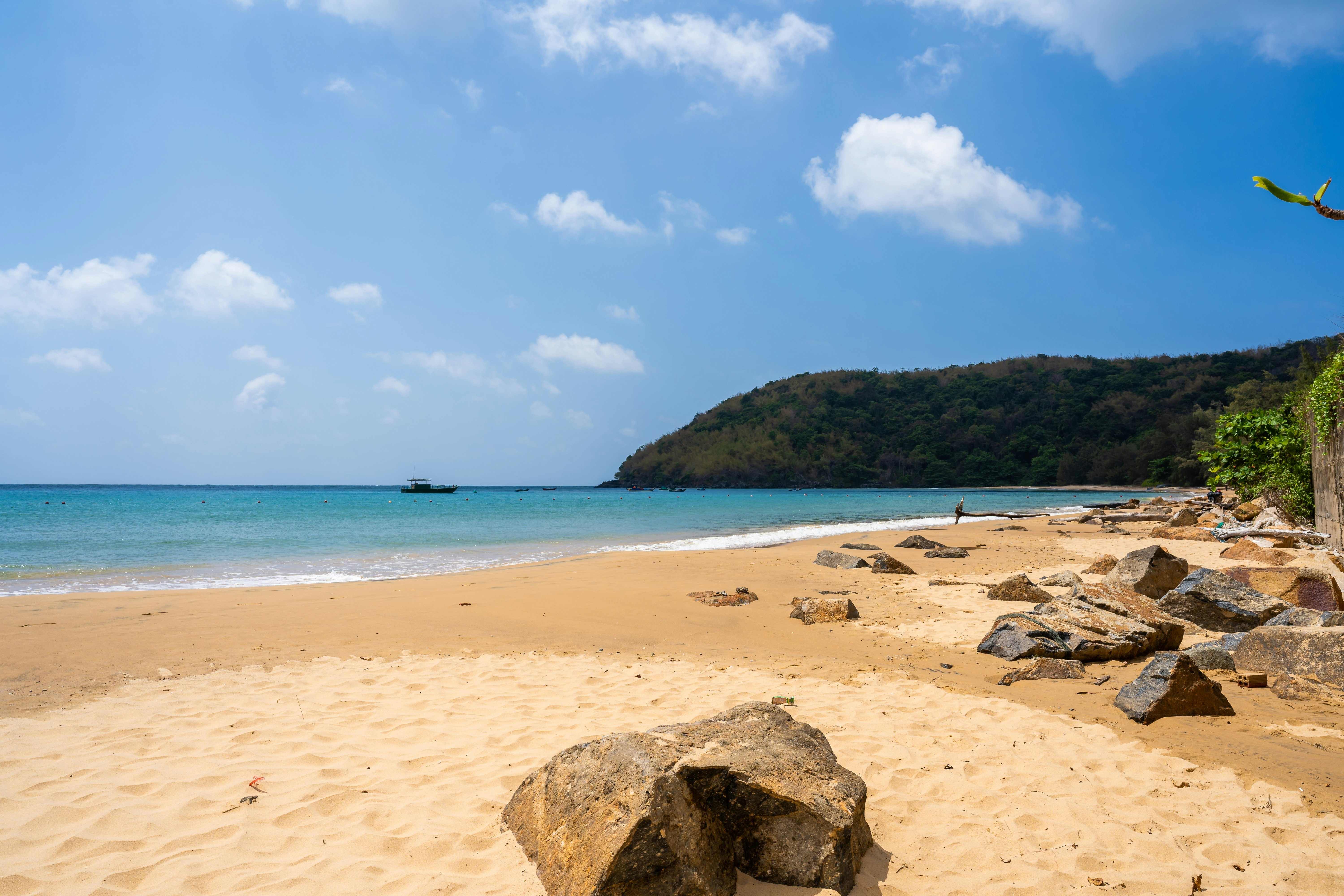 A deserted sandy beach with large boulders.