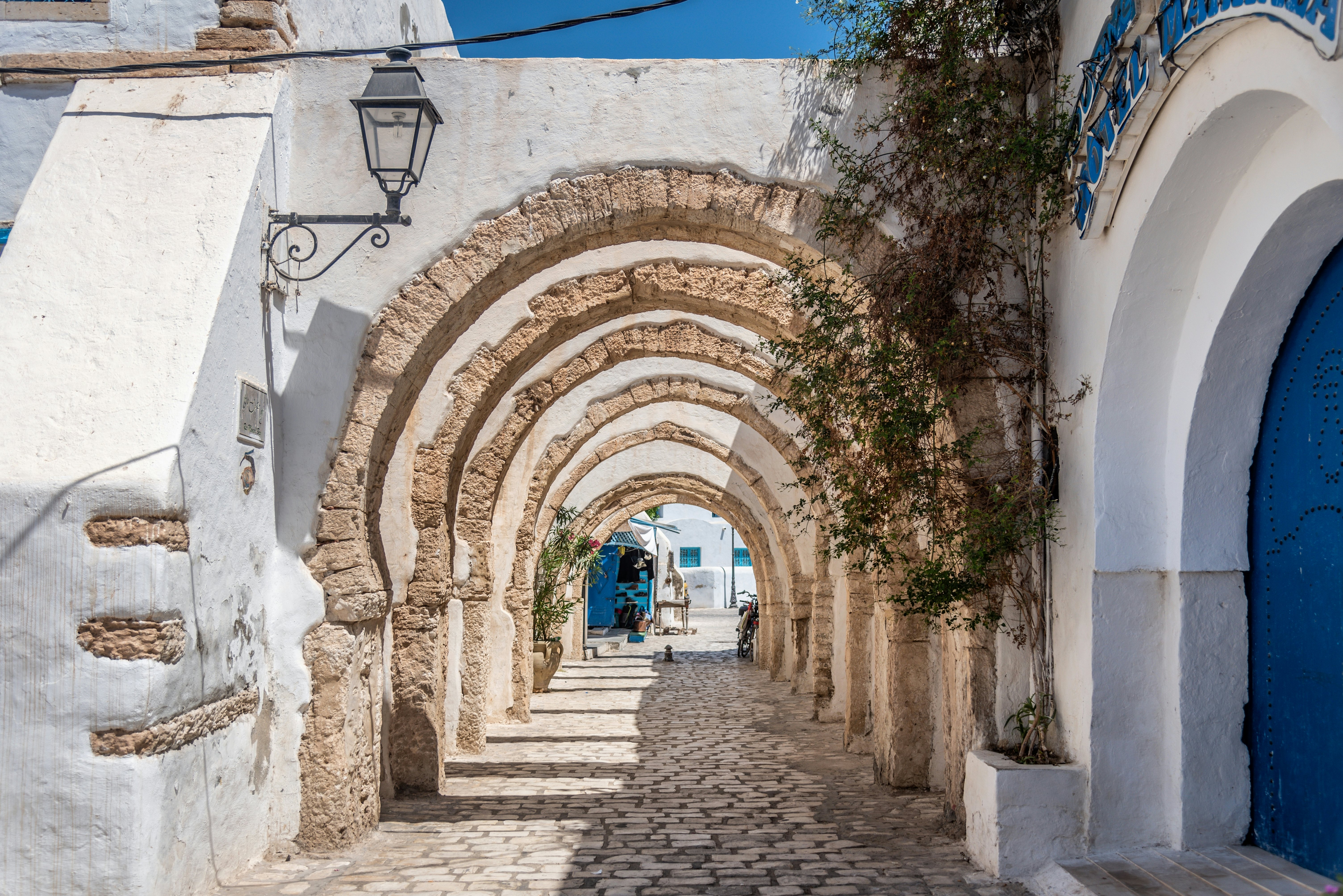 Narrow cobblestone street with white walls and blue doors