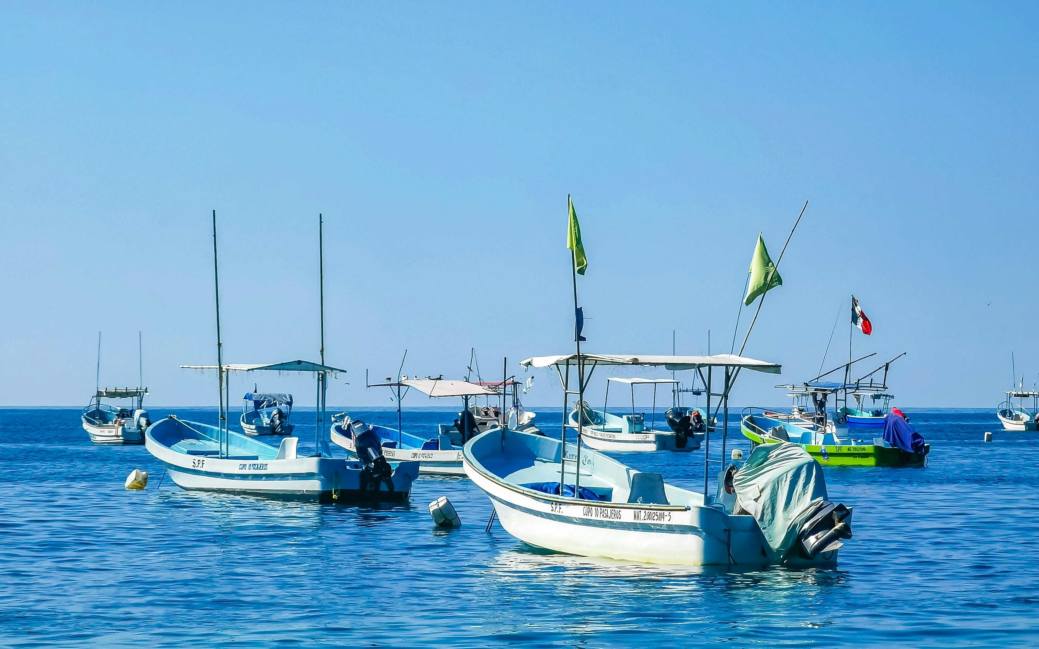 Small fishing boats, emtpy of people, moored in the ocean on a sunny day.
