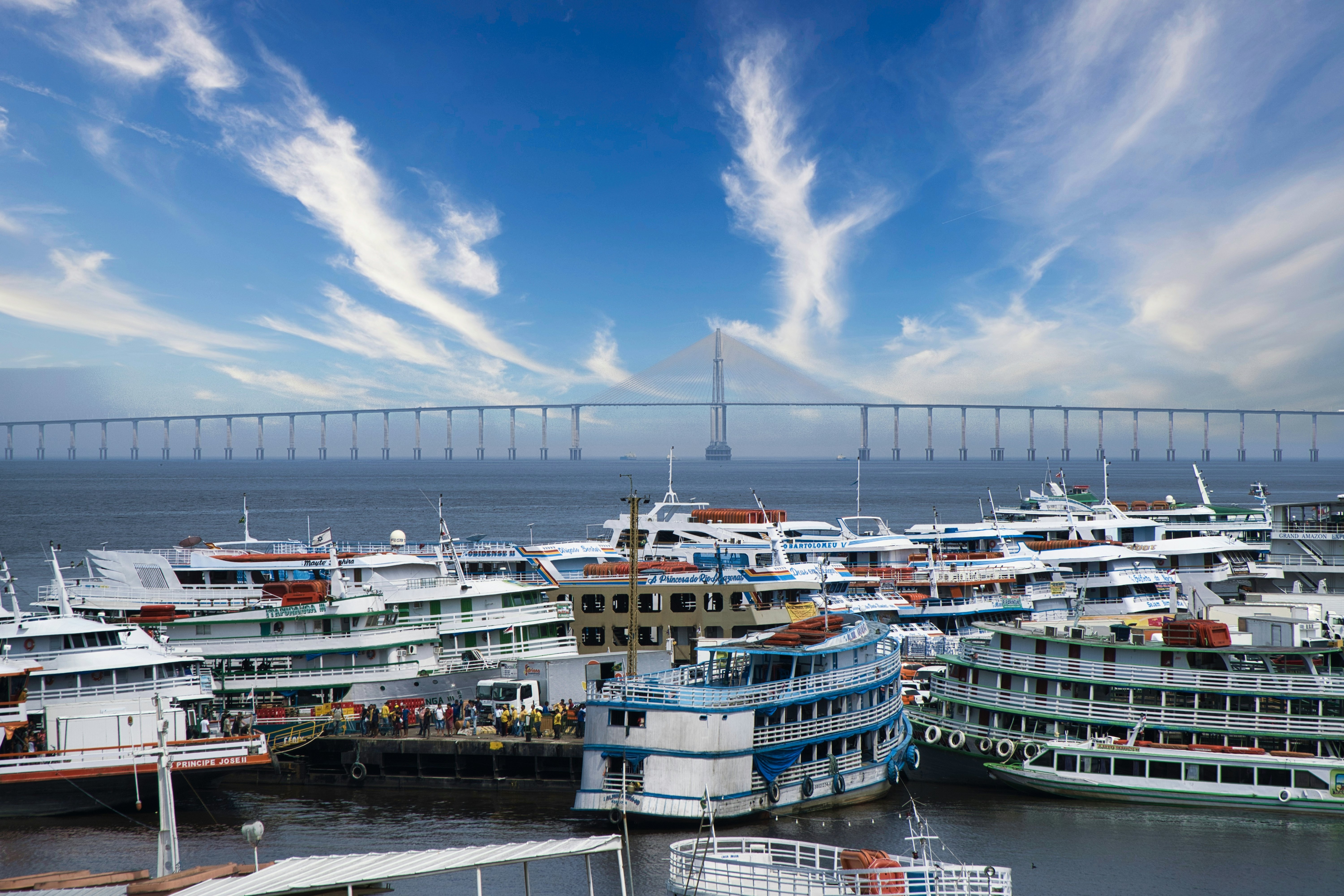 Photo of the Rio Negro with ships in the foreground and the Ponta Negra bridge in the background. Manaus, Amazonas, Brazil