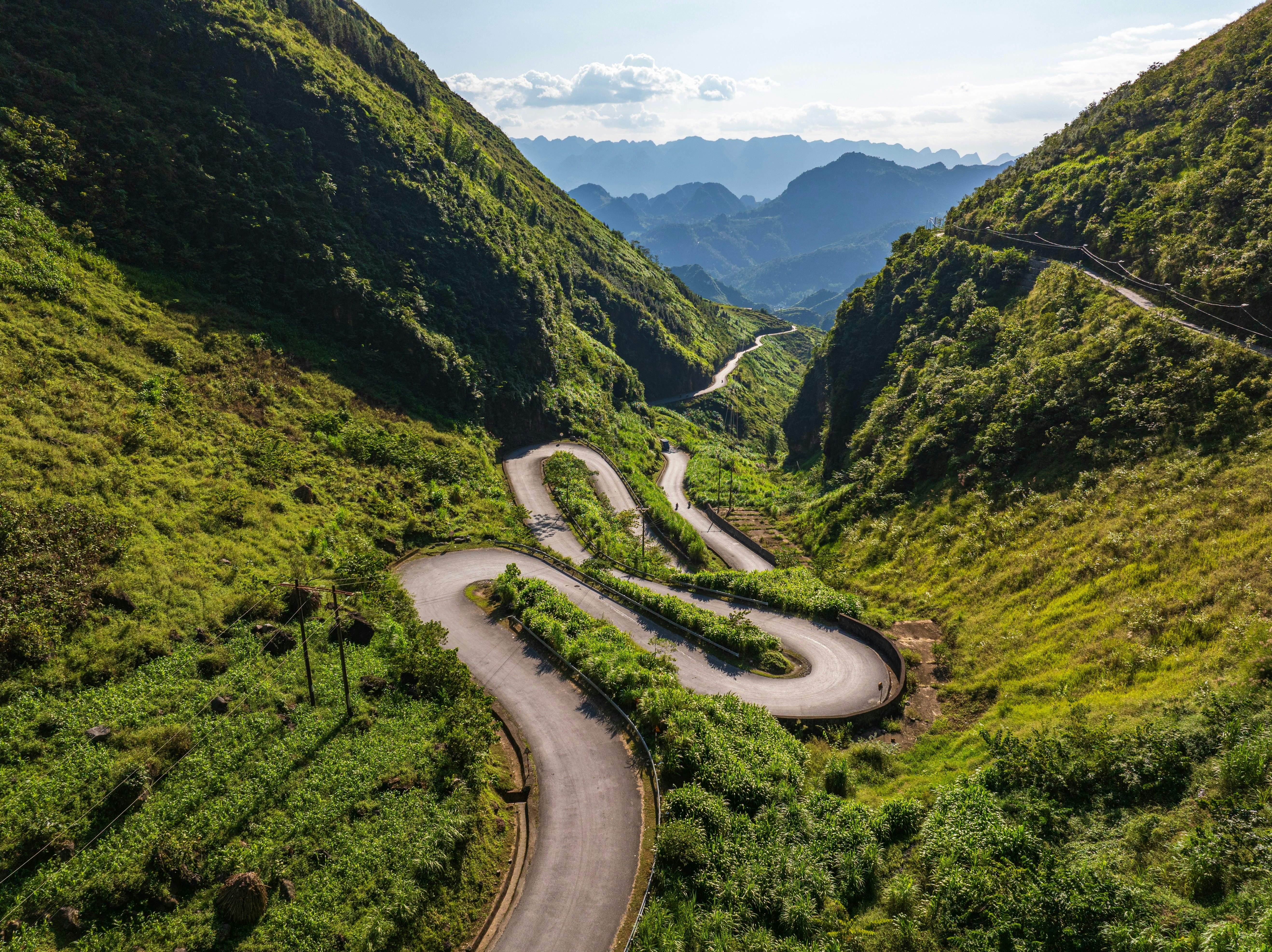 A windy road through a lush green mountain.