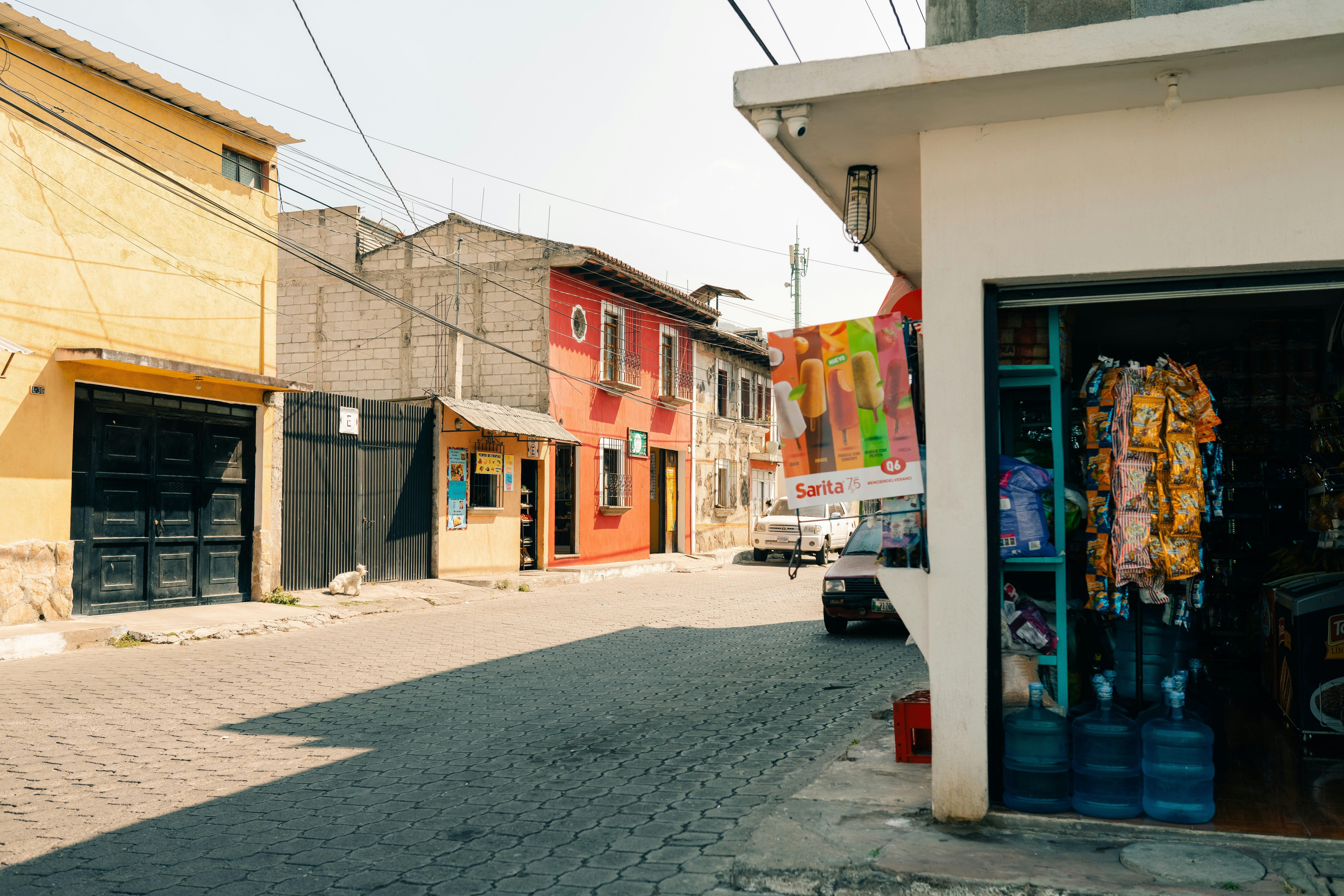A corner store along a cobblestone street on a sunny day.