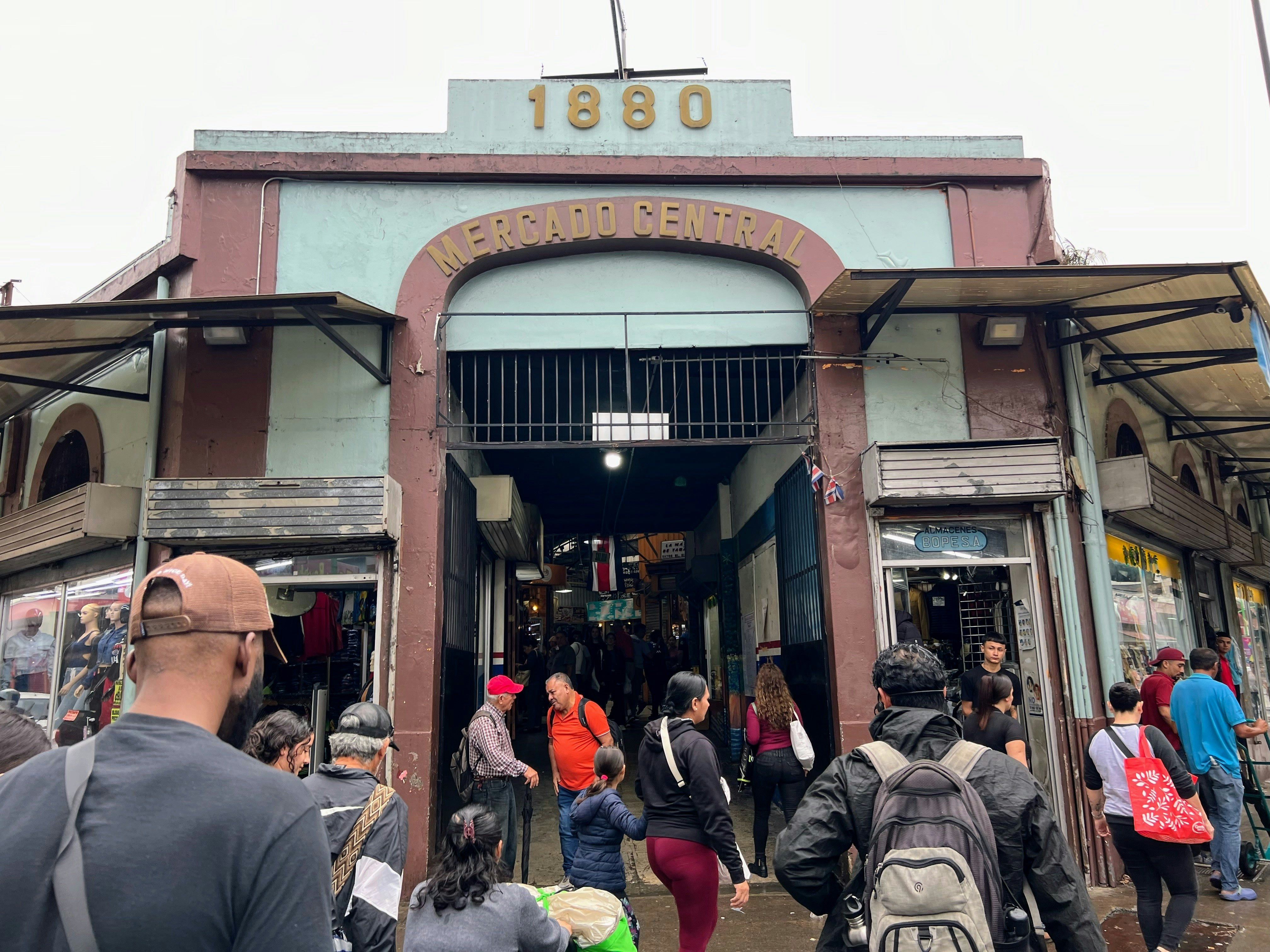 People walking into a brown and green building with the words "Mercado Central" above the entrance