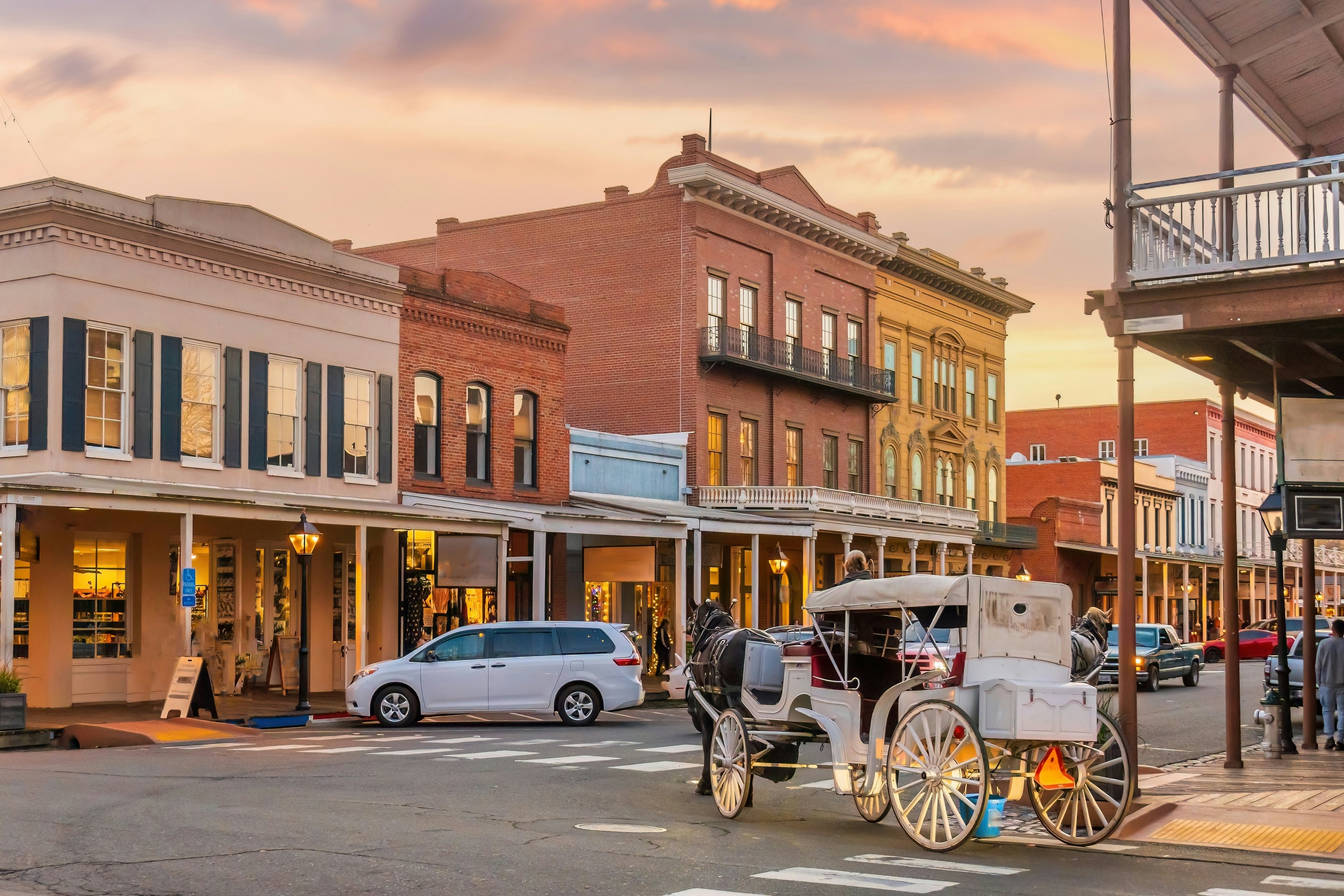 A horse-drawn carriage turns into a street lined with historic brick buildings.