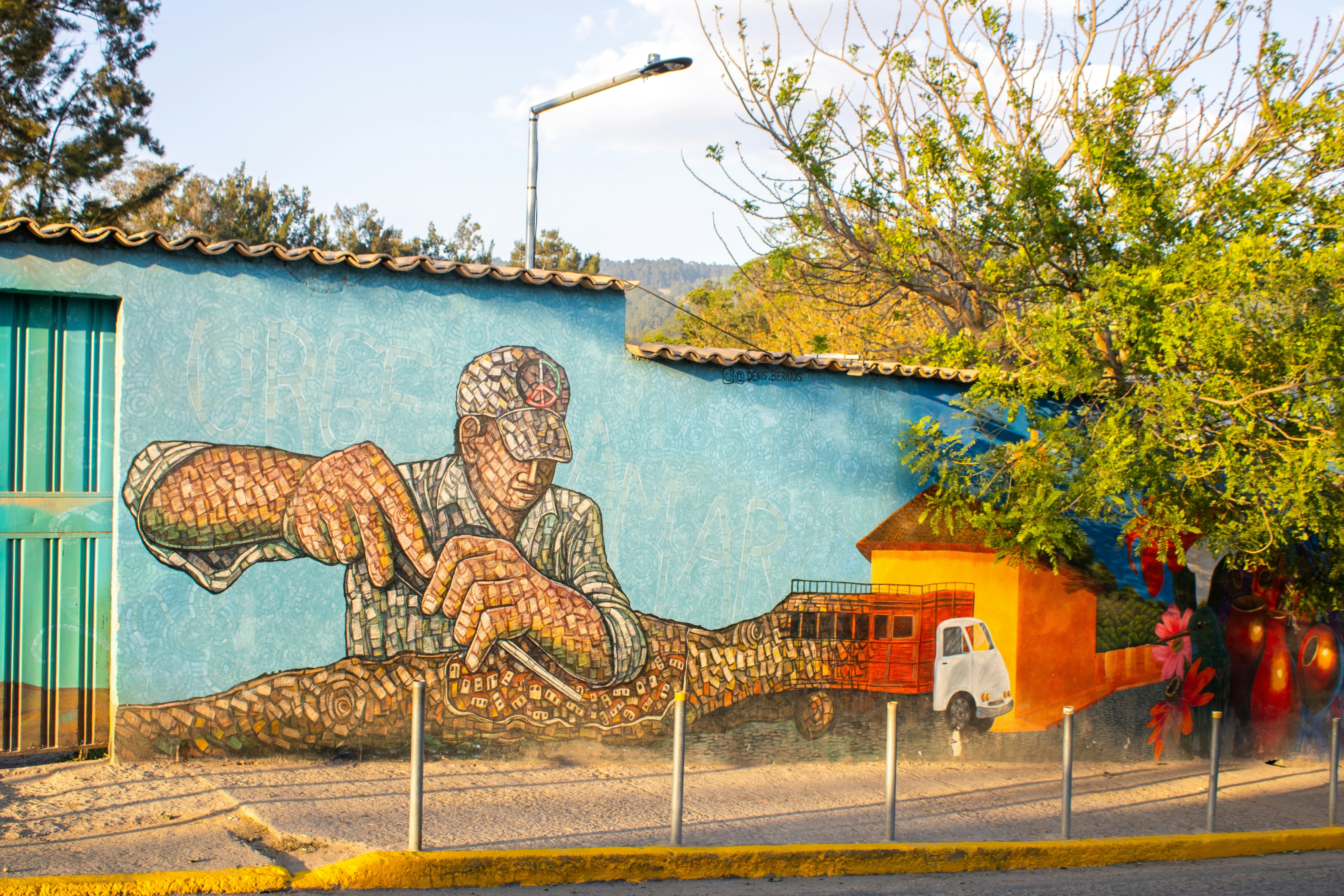 A street mural of a man shaping a series of small building blocks into tiny houses that emerge from the back of a truck.