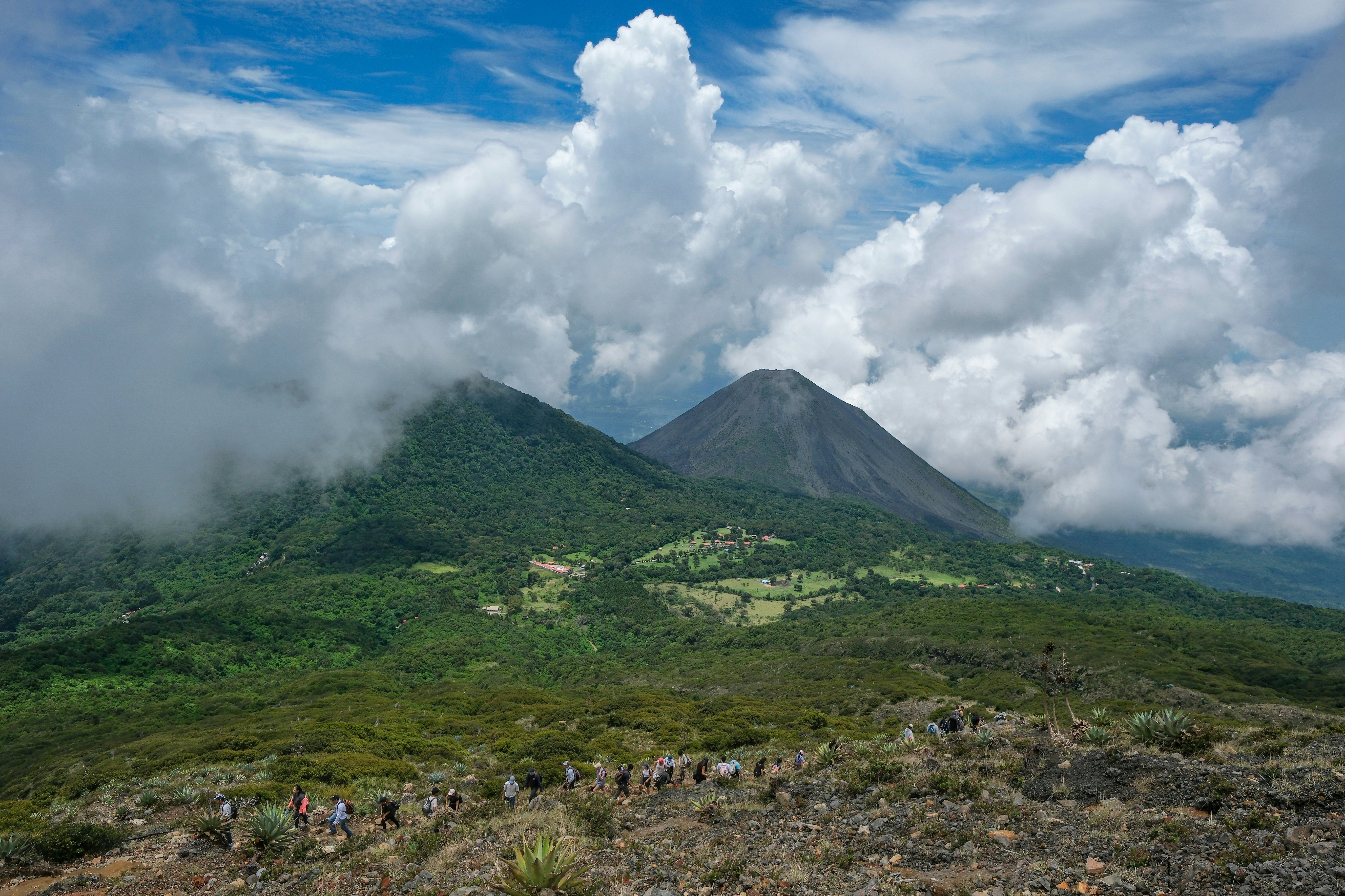 A view of two volcanoes. Low, poofy clouds are in the distance