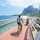 RIO DE JANEIRO - MARCH 19, 2016: Cyclist and scooter share the newly completed Ciclovia Tim Maia bike path, a legacy project from the 2016 Olympic Games connecting Ipanema and Copacabana with Barra., License Type: media, Download Time: 2025-05-22T13:23:20.000Z, User: lonelyplanetmedia, Editorial: true, purchase_order: 65050 - Digital Destinations and Articles, job: Global Publishing WIP, client: Global Publishing WIP, other: Pia Peterson Haggarty // SS Comp Ingestion
