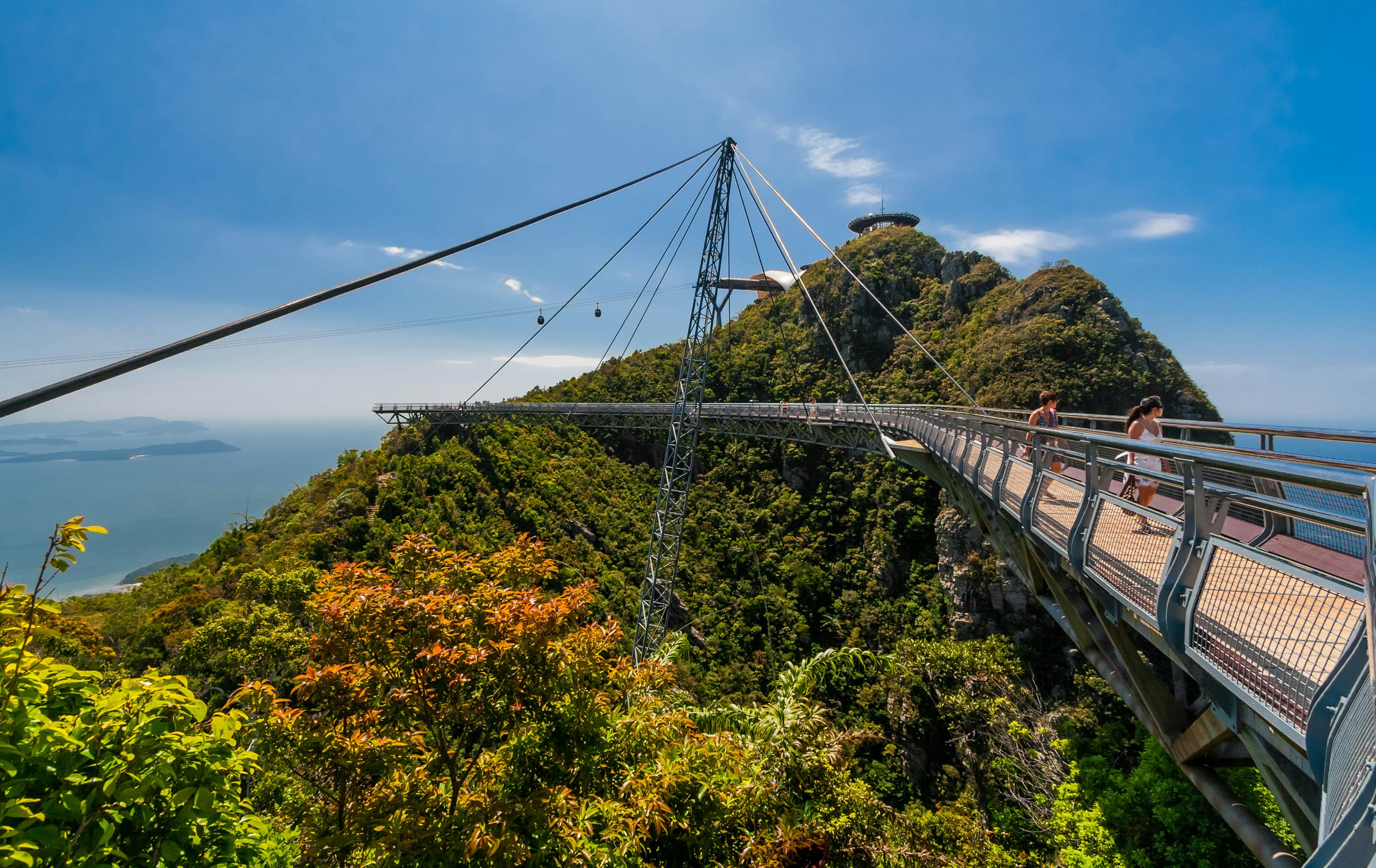 Visitors walking along the single-pylon Langkawi Sky Bridge. There are two gondolas near the cable-car top station in the background.
1126870001
admiring, amazing, architecture, asia, attraction, background, bridge, cable car, cable-stayed, cables, curved, female, gondolas, great scene, gunung, hanging, hilltops, holiday, island, kedah, landscape, langkawi, machinchang, malaysia, mat chinchang, mountain, outdoor, peak, pedestrian, platform, pylon, railings, scenic, sea, sky, sky bridge, steel, suspended, top station, tourism, tourists, trees, triangular, tropical, vacation, view, visitors, walking, walkway, women