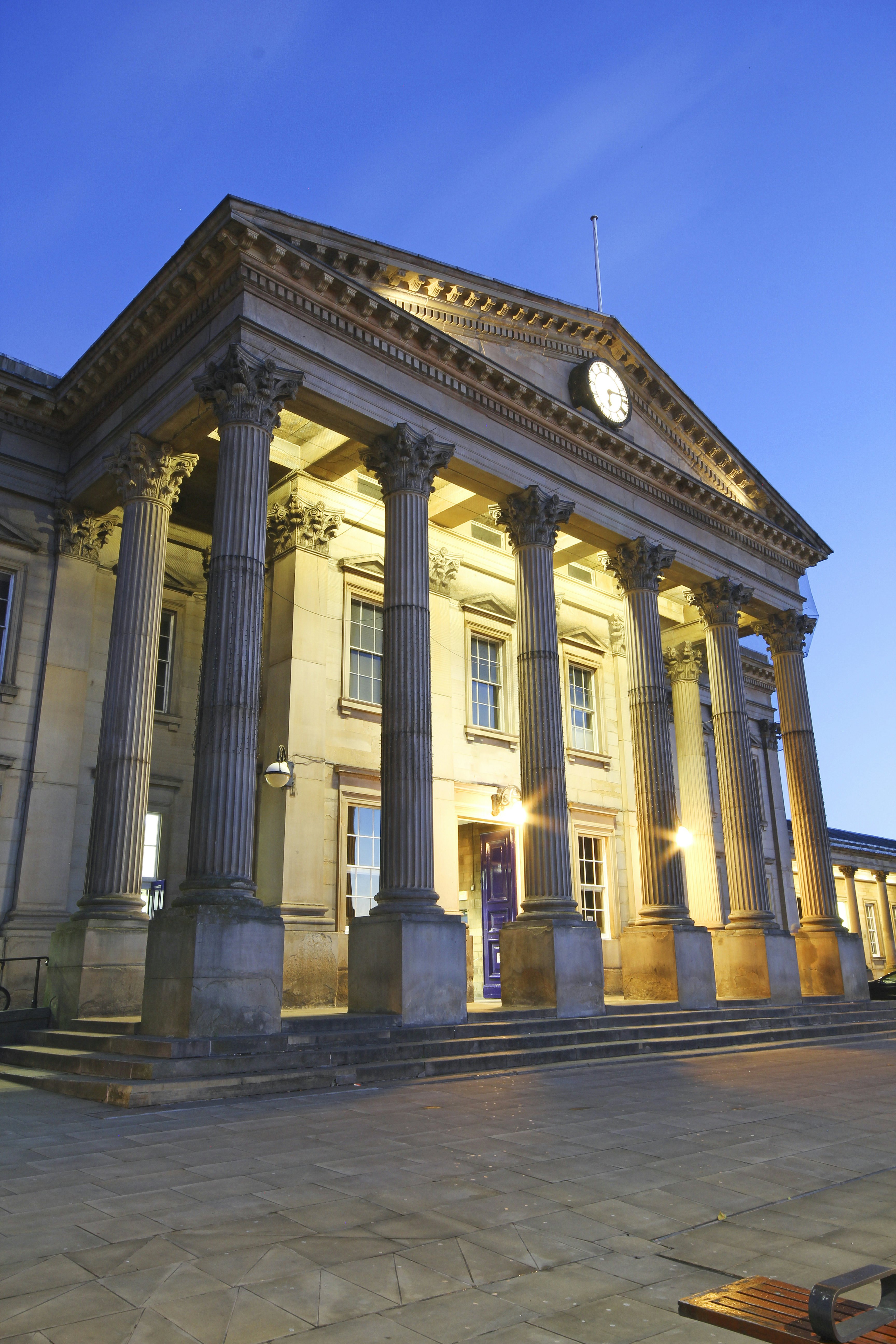 A grand facade of a building, with large stone columns and a clock.