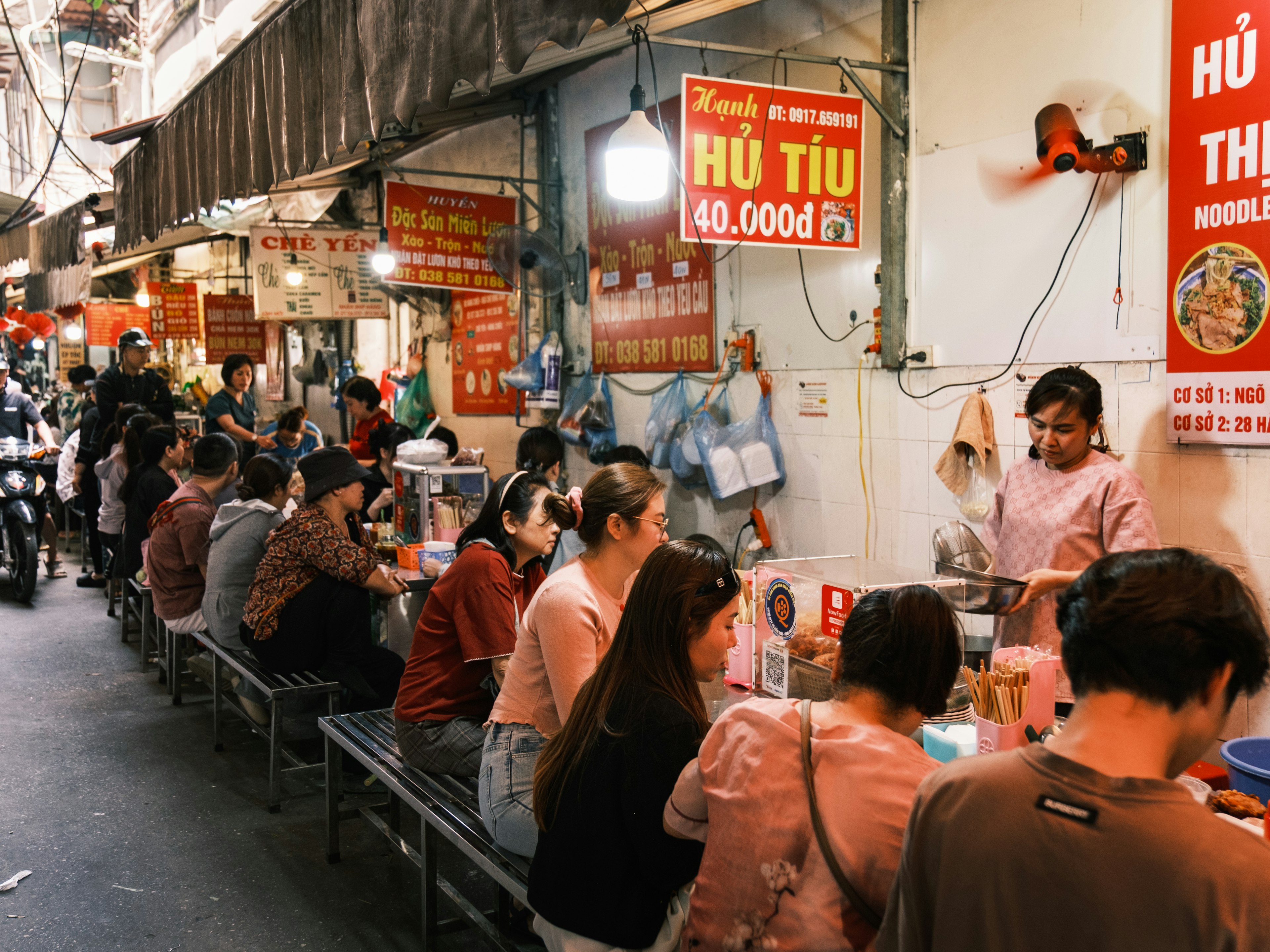 People sitting on benches eating food outdoors along a wall