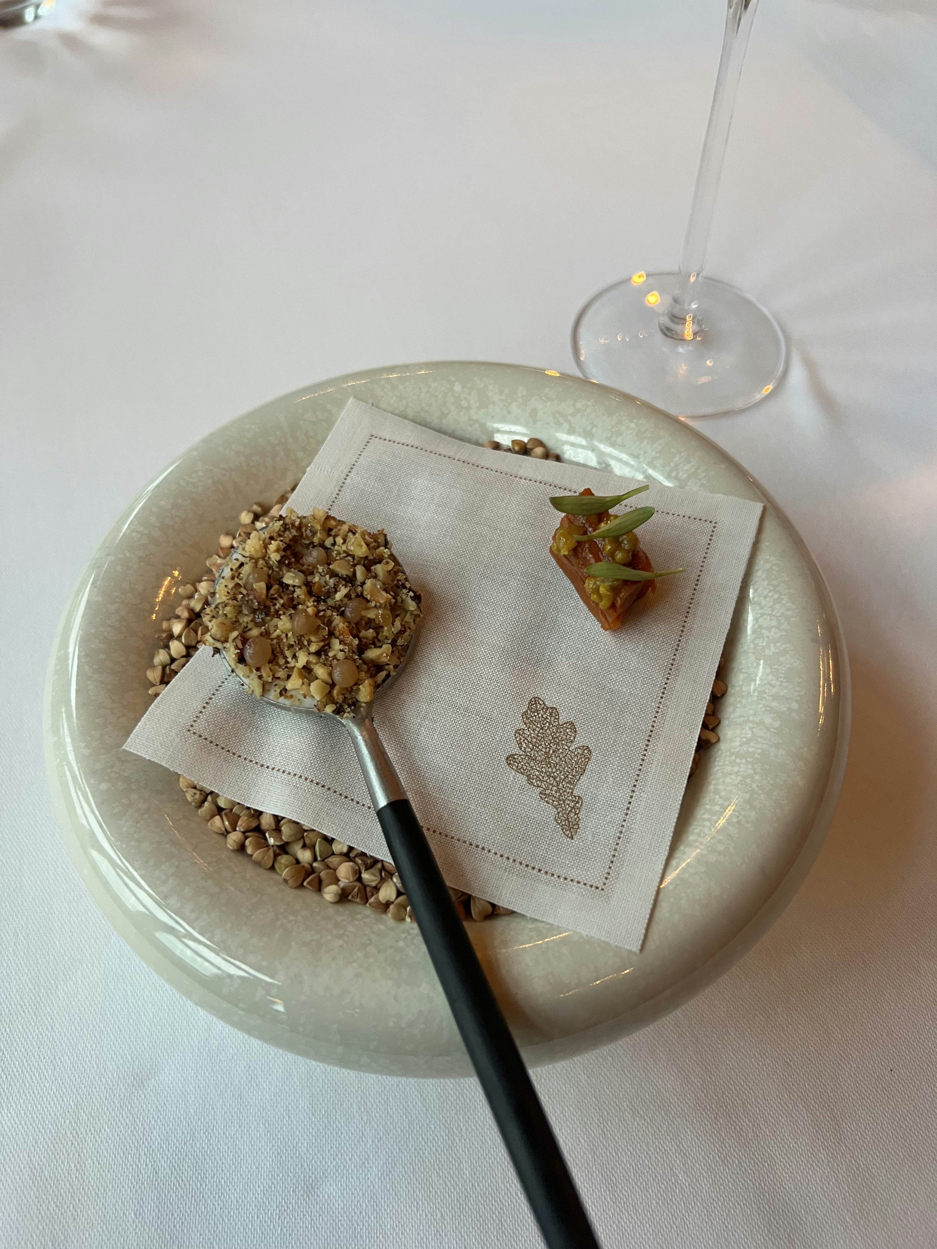A round dish of grain with a spoon resting on a napkin.