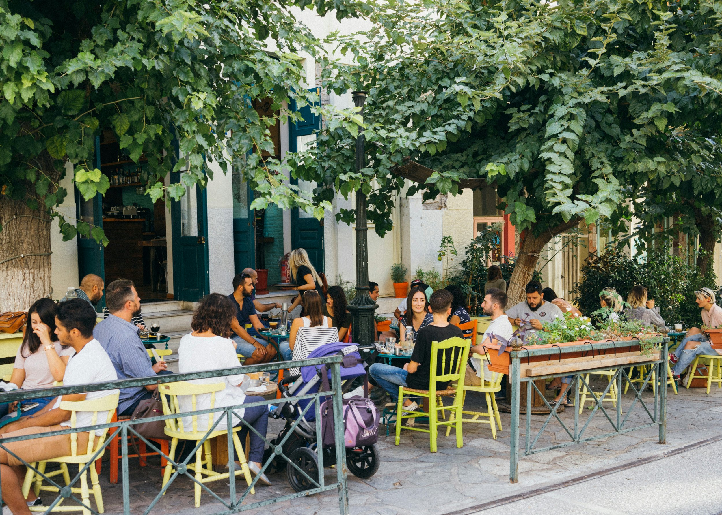 People sitting outside in colorful chairs at a cafe