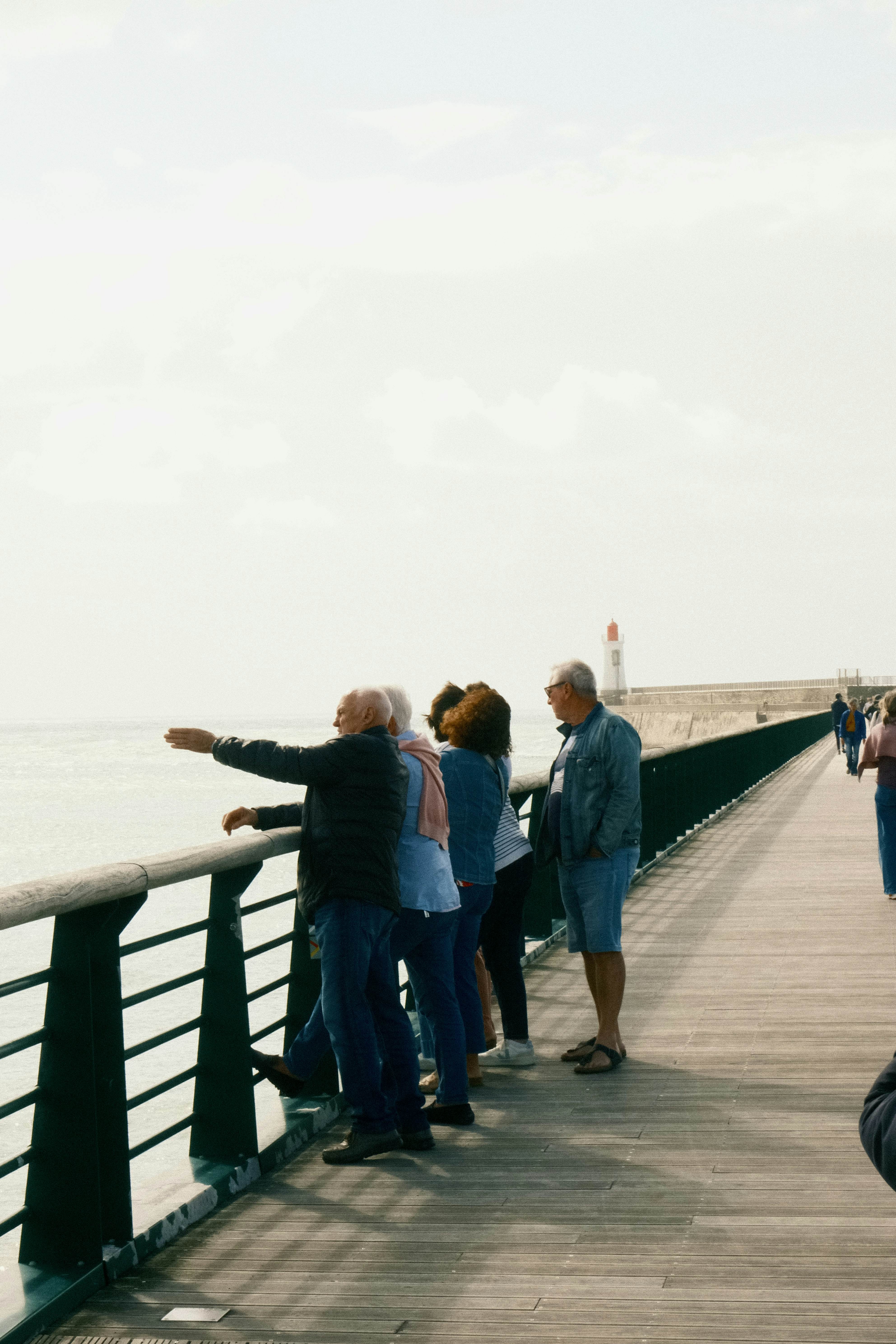 Sightseeing in la Chaume, Les Sables d'Olonne, Vendée, France - tourists on the grande jetée with a lighthouse in the background