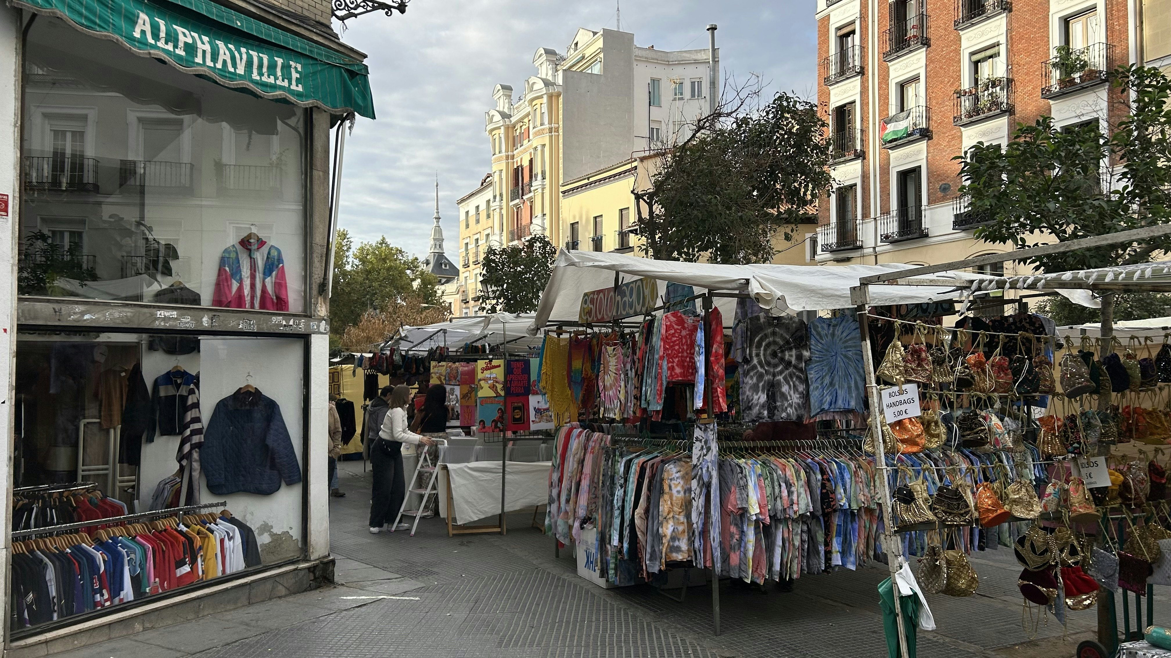 Clothing and other items hang on lines in booths at an outdoor market