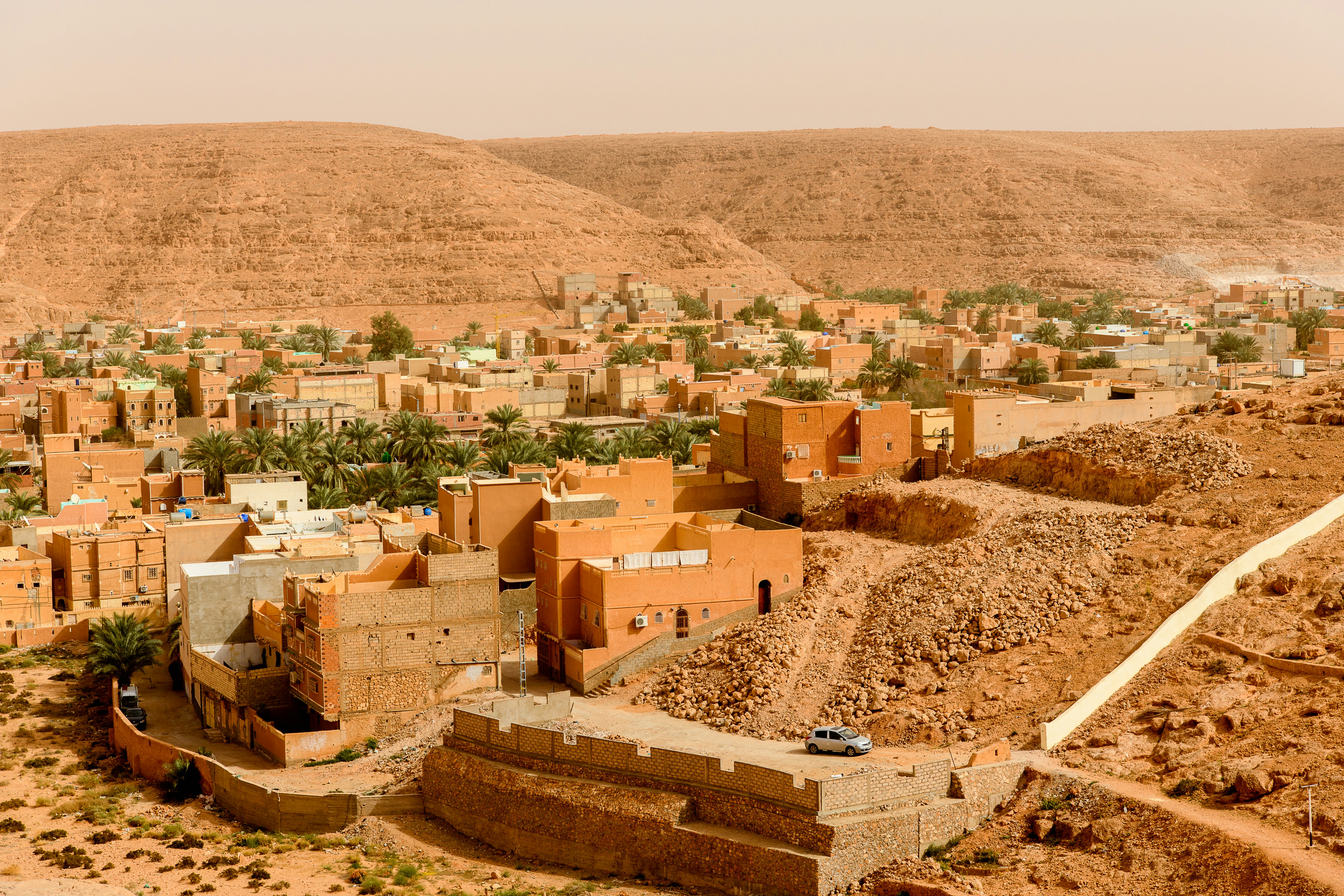 An oasis town in a desert with low-rise square buildings in golden hues that blend into the landscape.