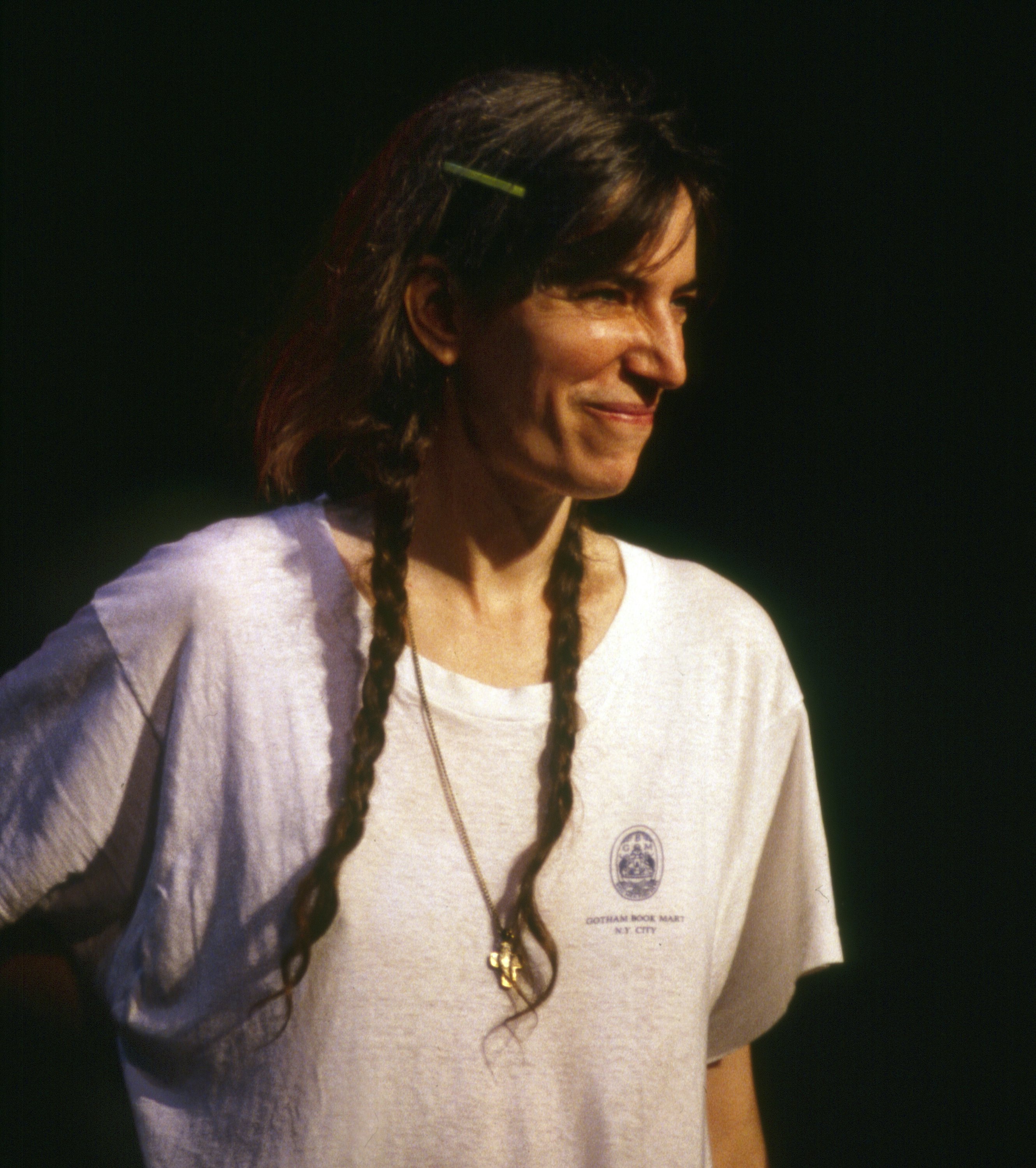 Close up of a woman with long brown hair smiles while wearing a white tshirt