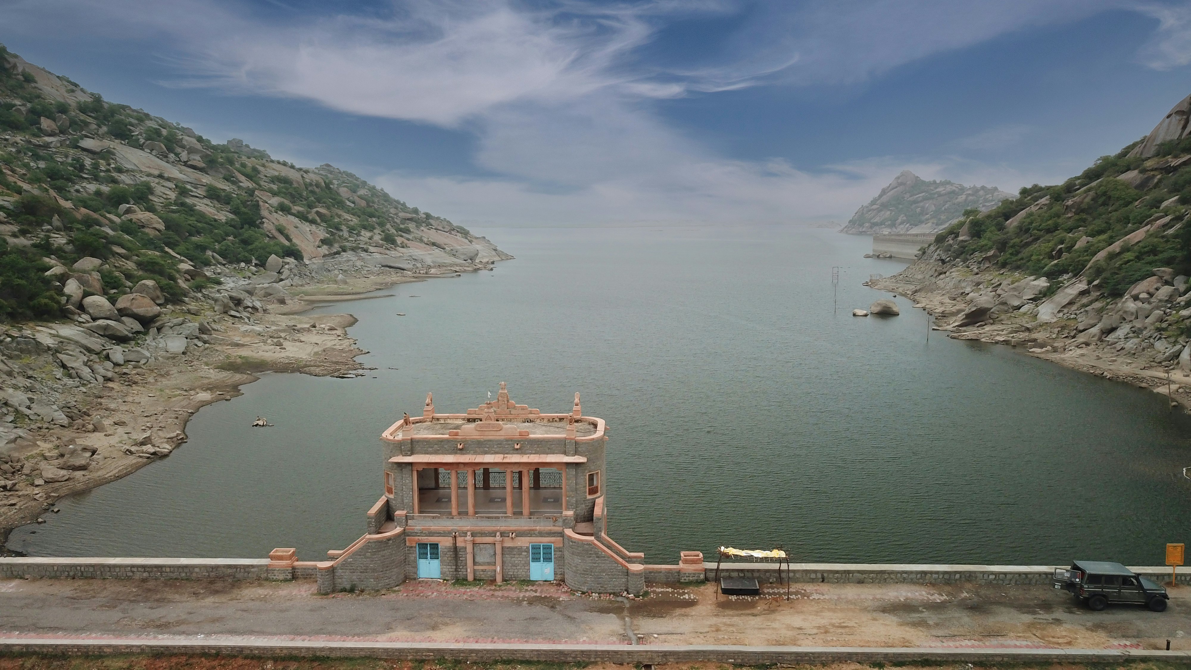 A dam across a waterway with boulder-covered hills on either side.