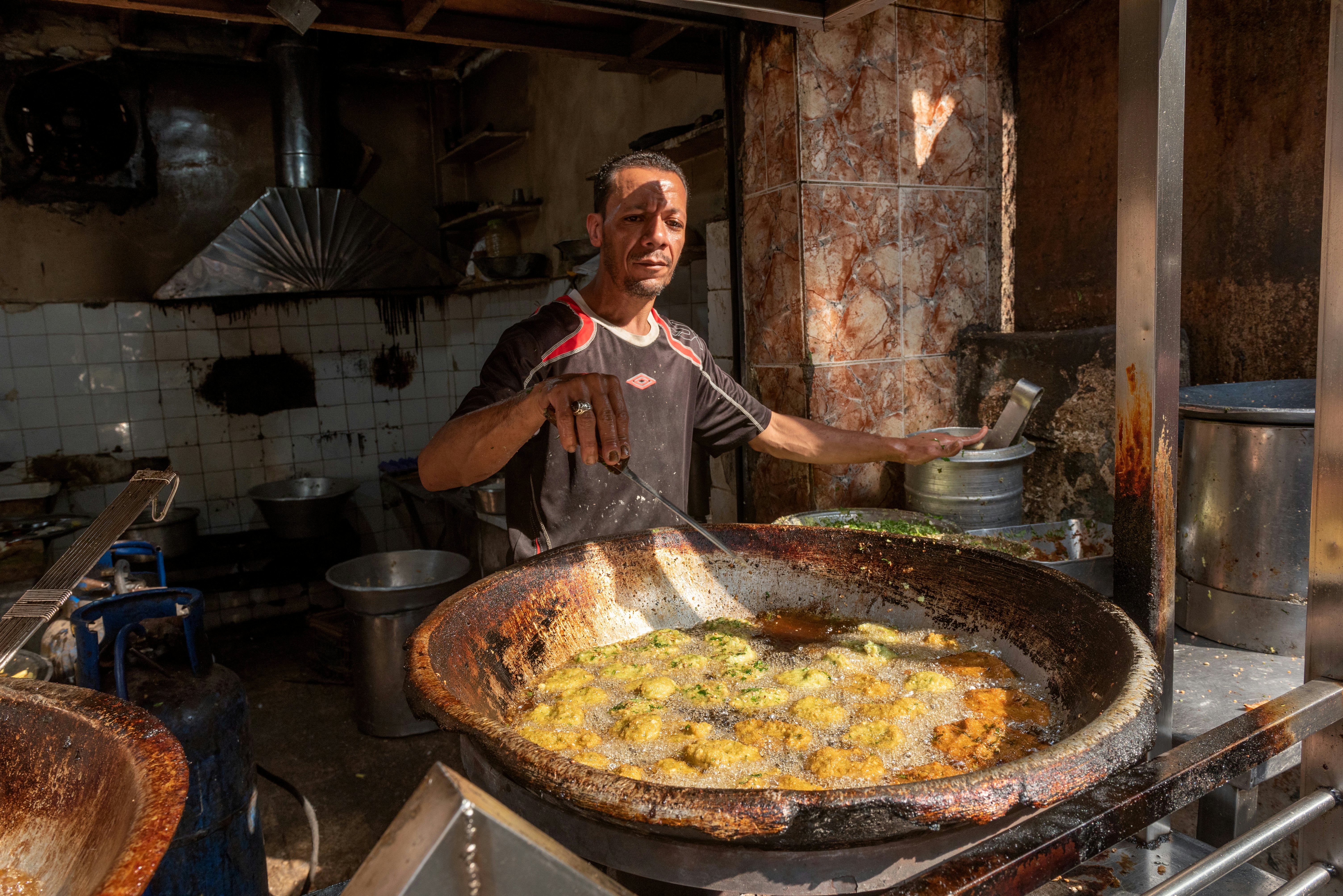 An Egyptian man frying ta’amiyya (fava bean fritters) in Cairo, Egypt.