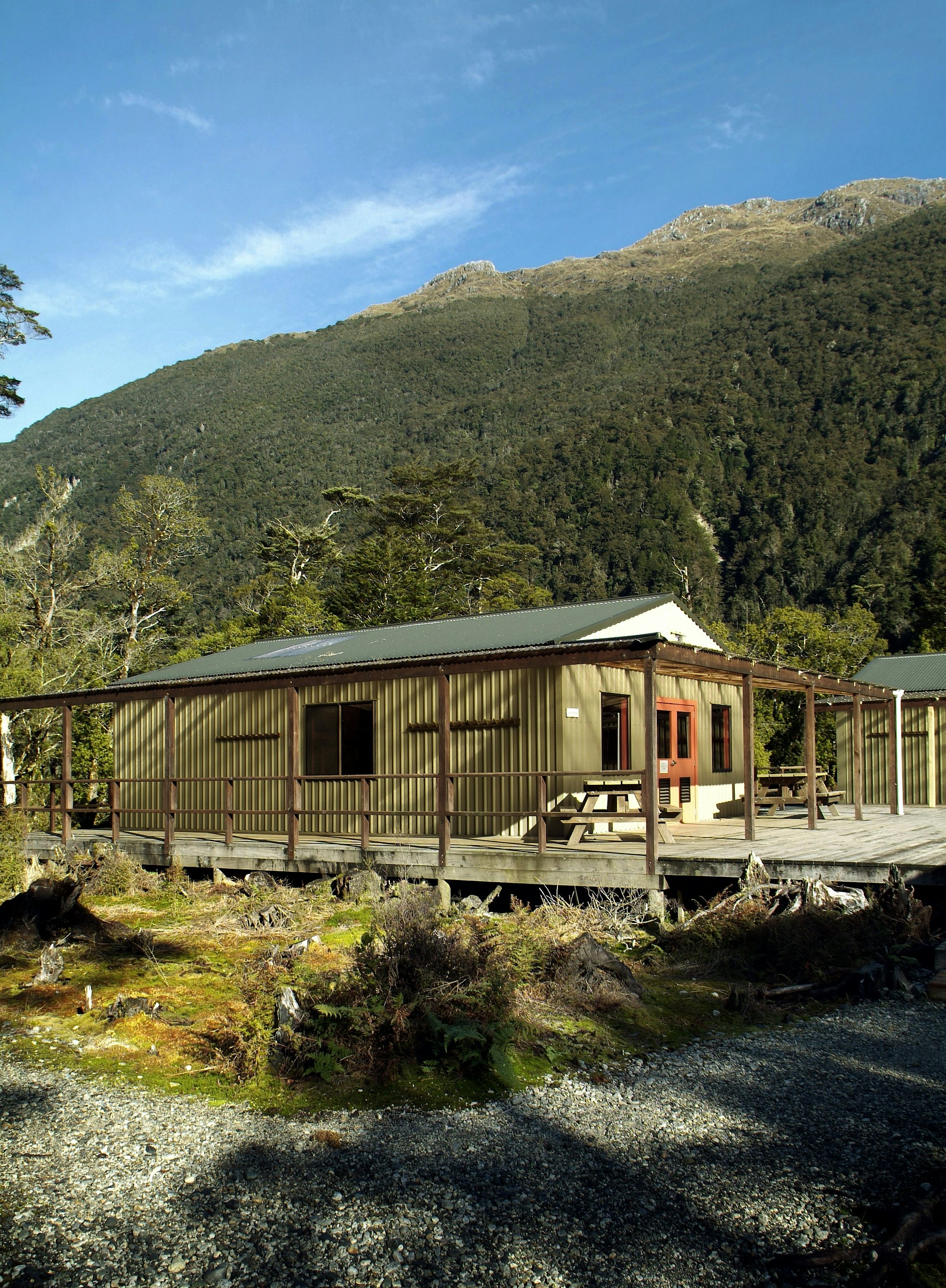 A basic hut on a hiking trail at the foot of a large hill.