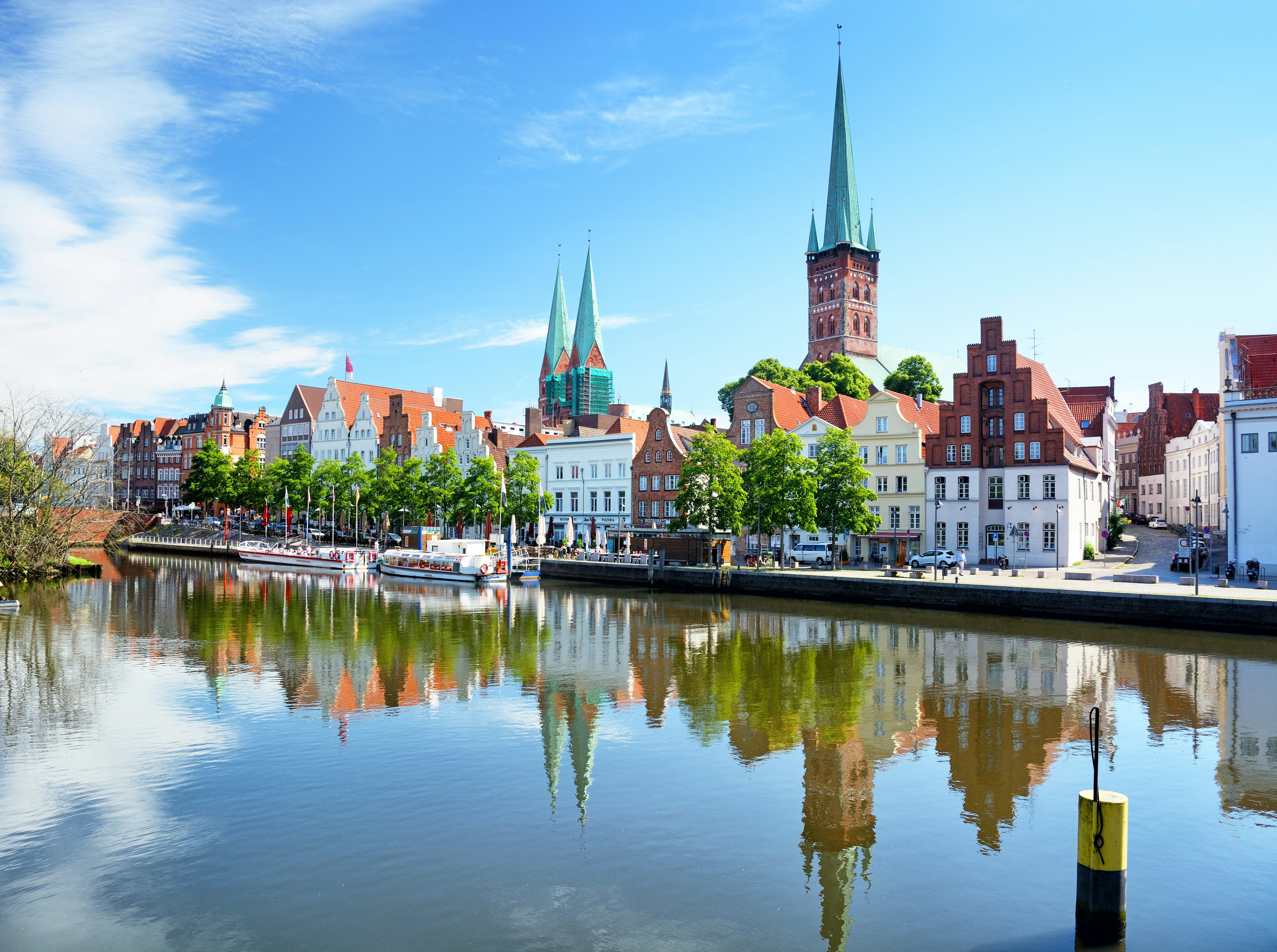 Wide shot of historic Old City buidings lining, and reflected in, a narrow waterway on a sunny day.