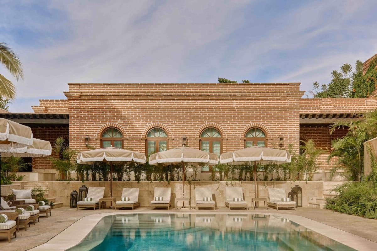 A building with a pool and lounge chairs under umbrellas