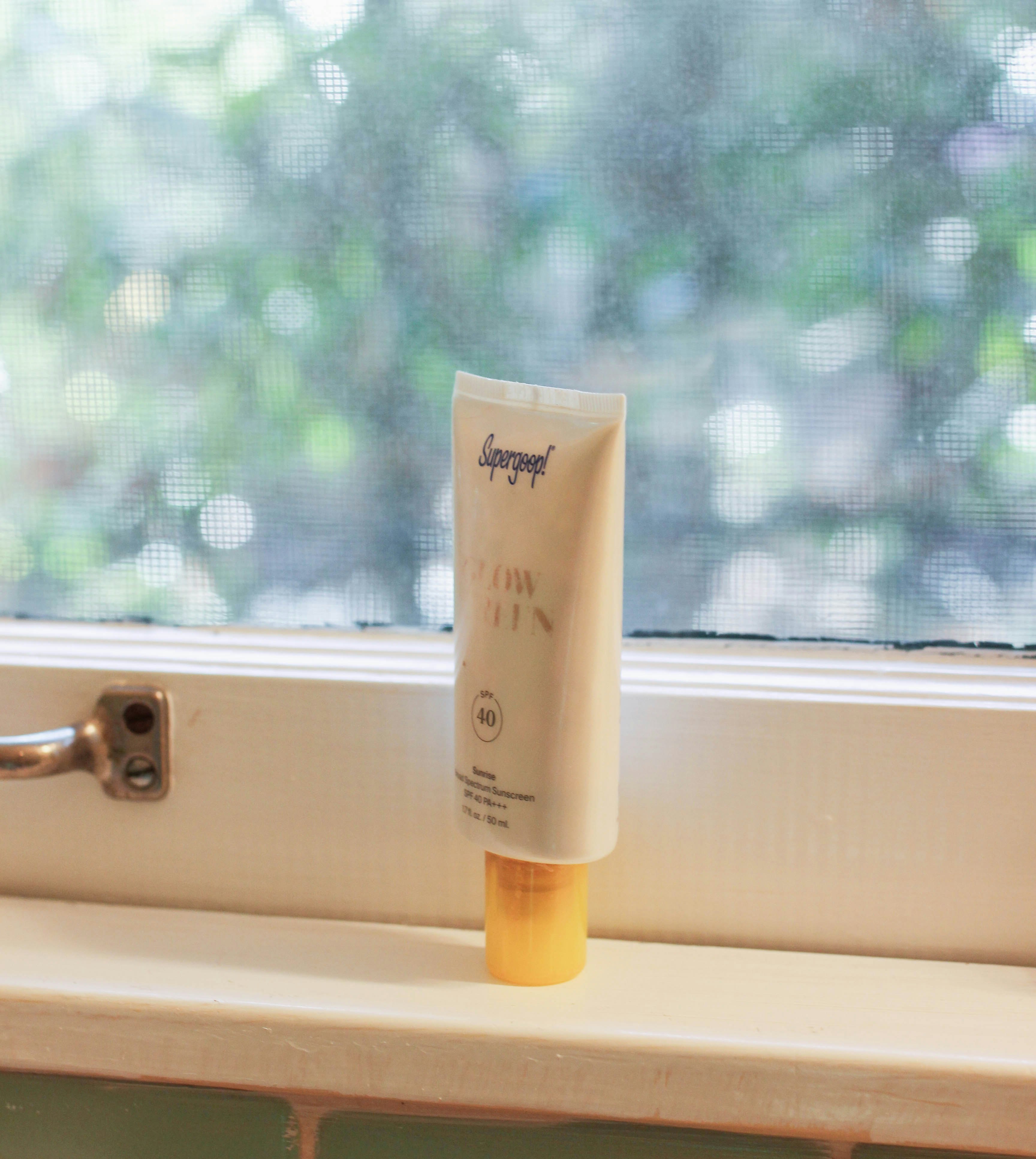 A tube of sunscreen is presented on a windowsill in a bathroom.