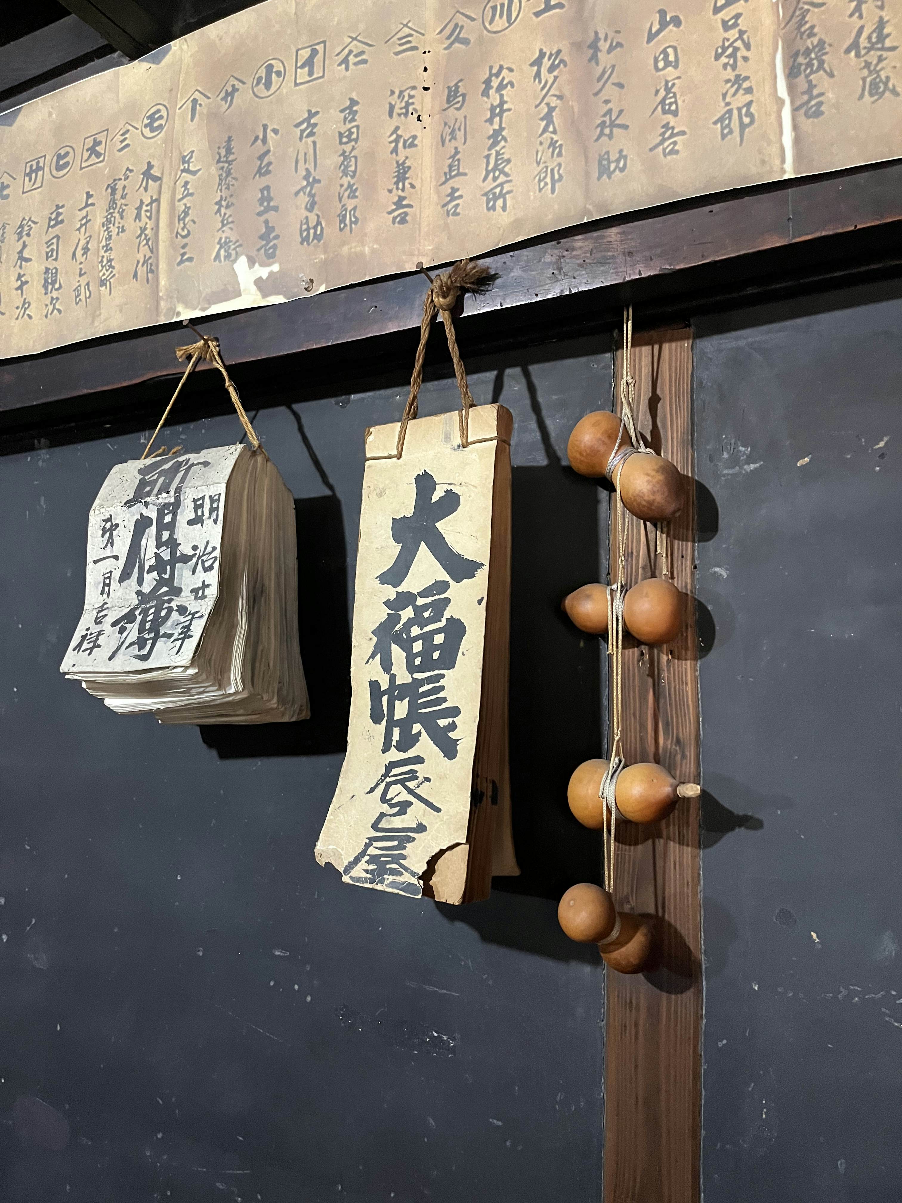 Japanese script on small pads of paper hanging by string on a wall.