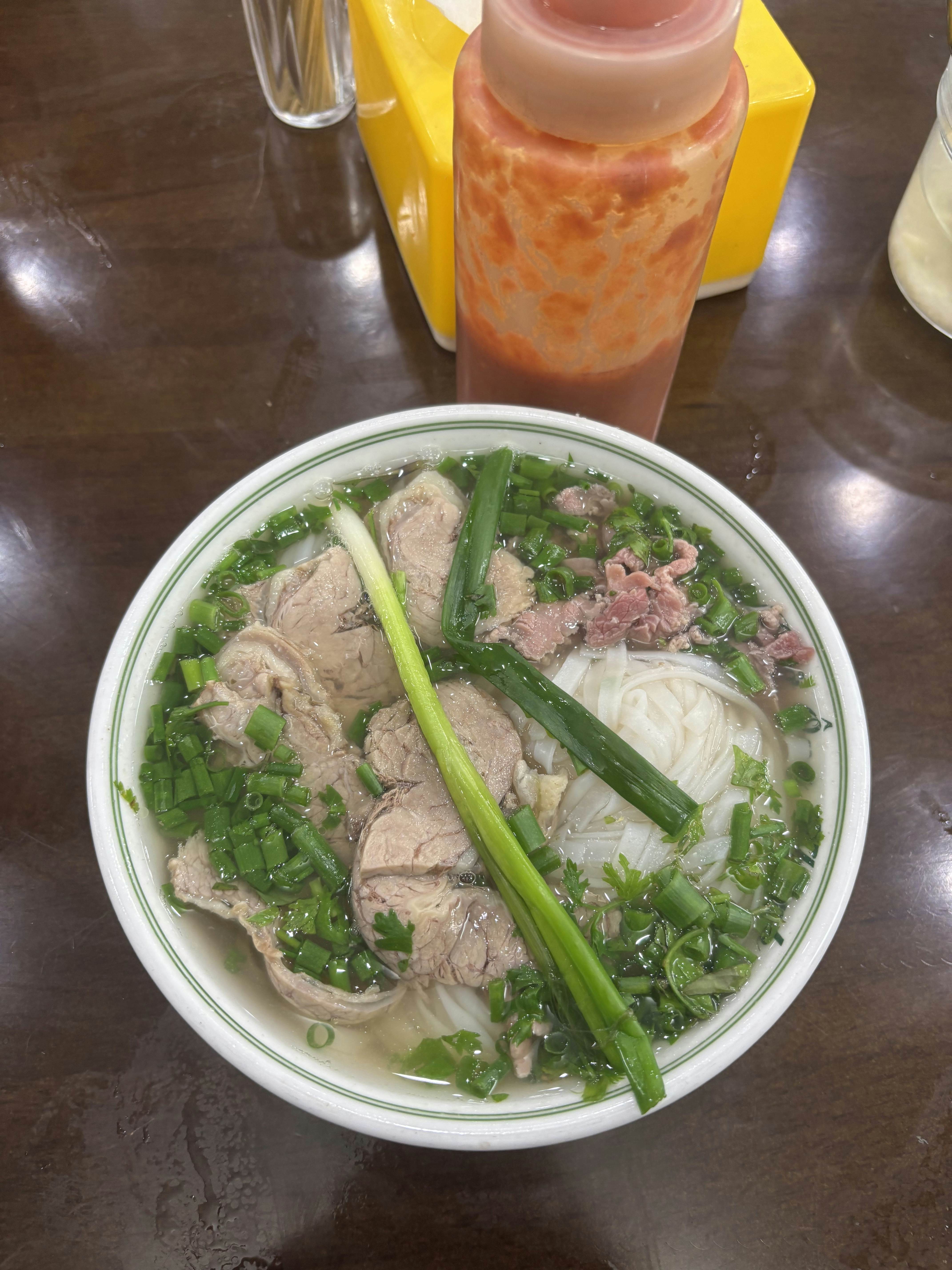A bowl of light broth with meat and vegetables