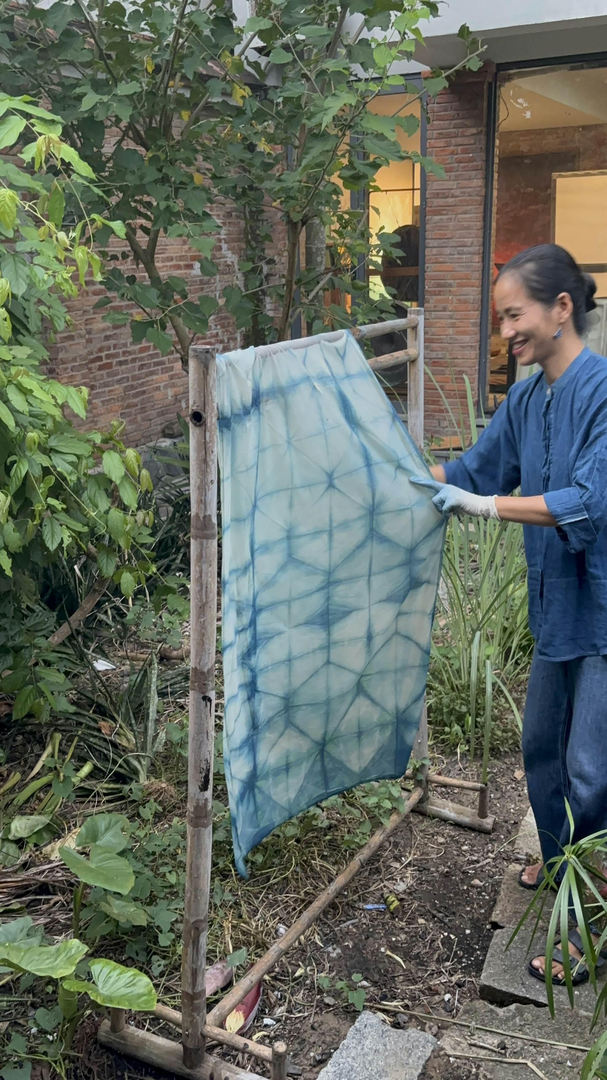 A woman handles a dyed piece of fabric on an outdoor rack