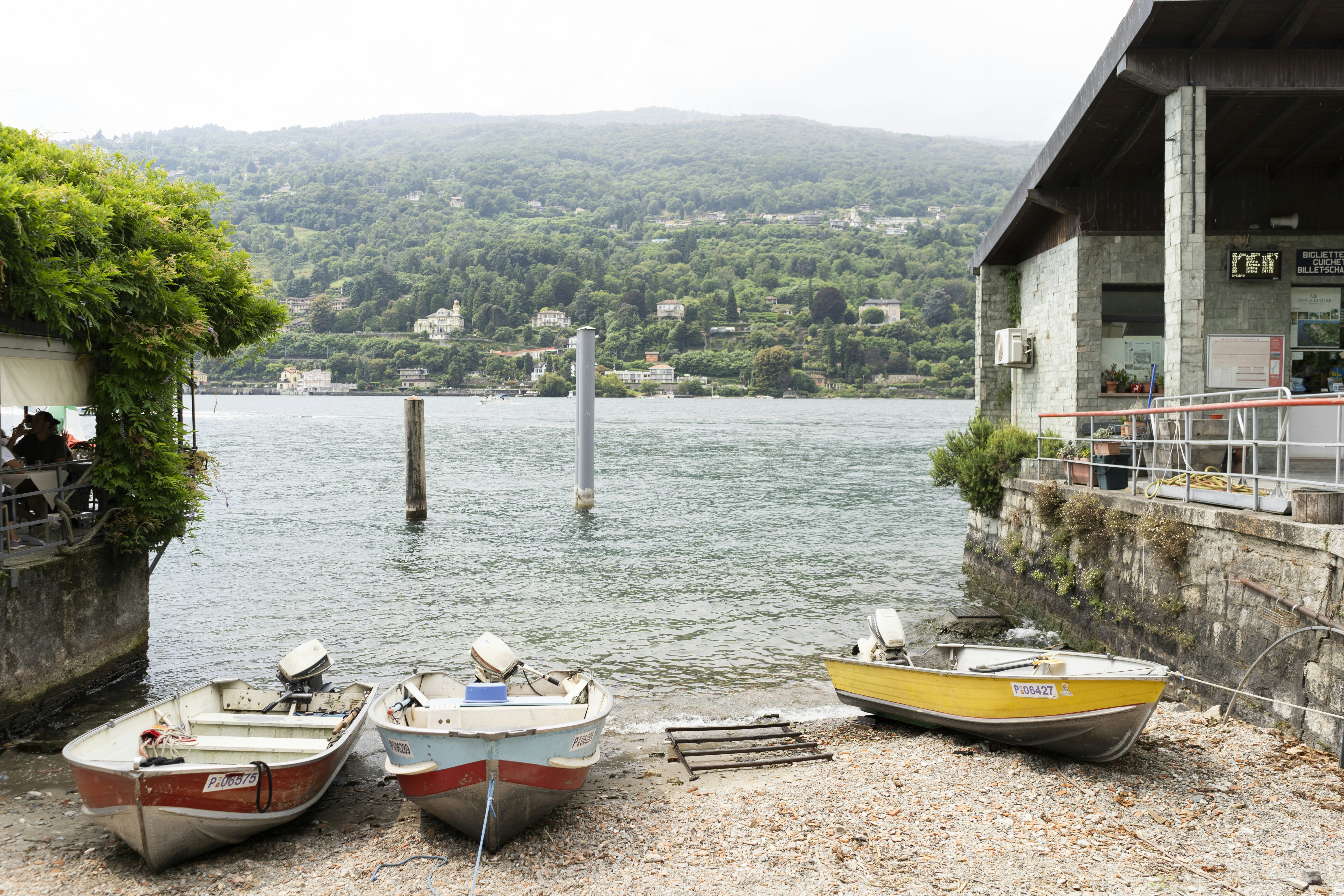 Two small boats are docked on a small harbor. There are restaurants on either side that overlook a lake.